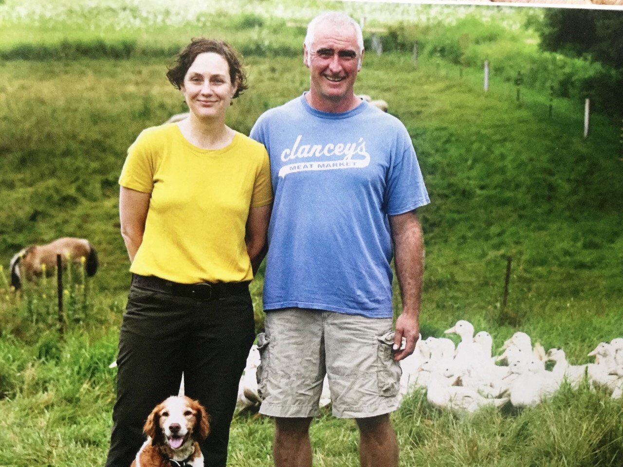 Au Bon Canards owners standing in a field with their dog with ducks in the background