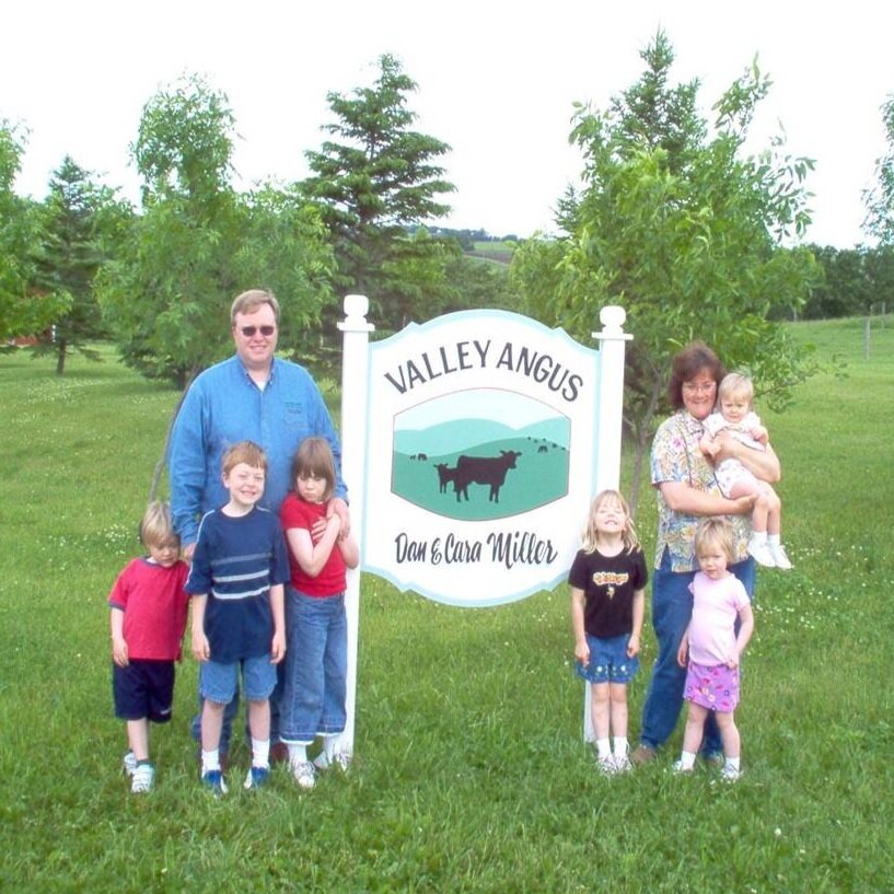 Family photo of the Valley Organic Farmers standing by their farm sign