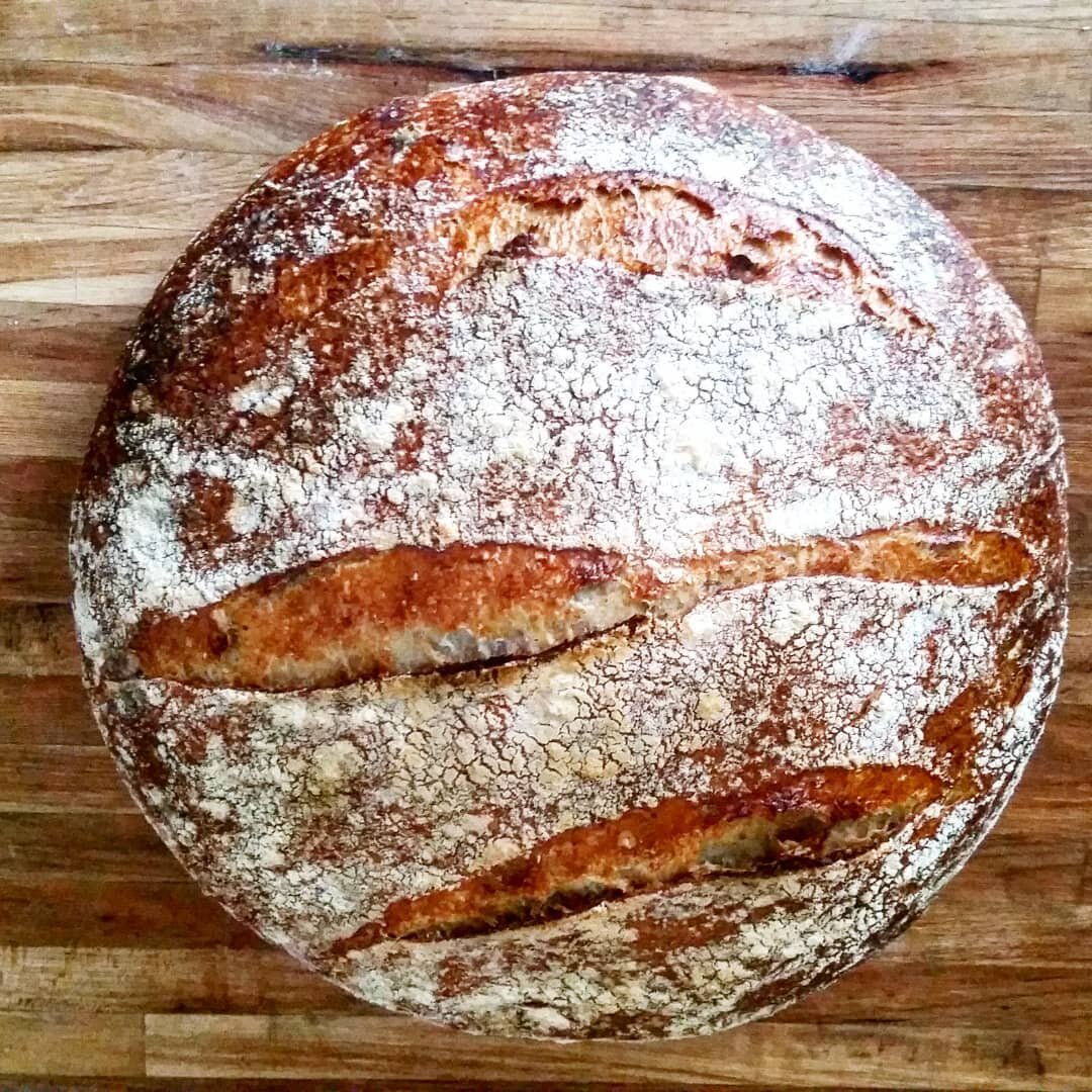 A flour-dusted round loaf sitting on a cutting board