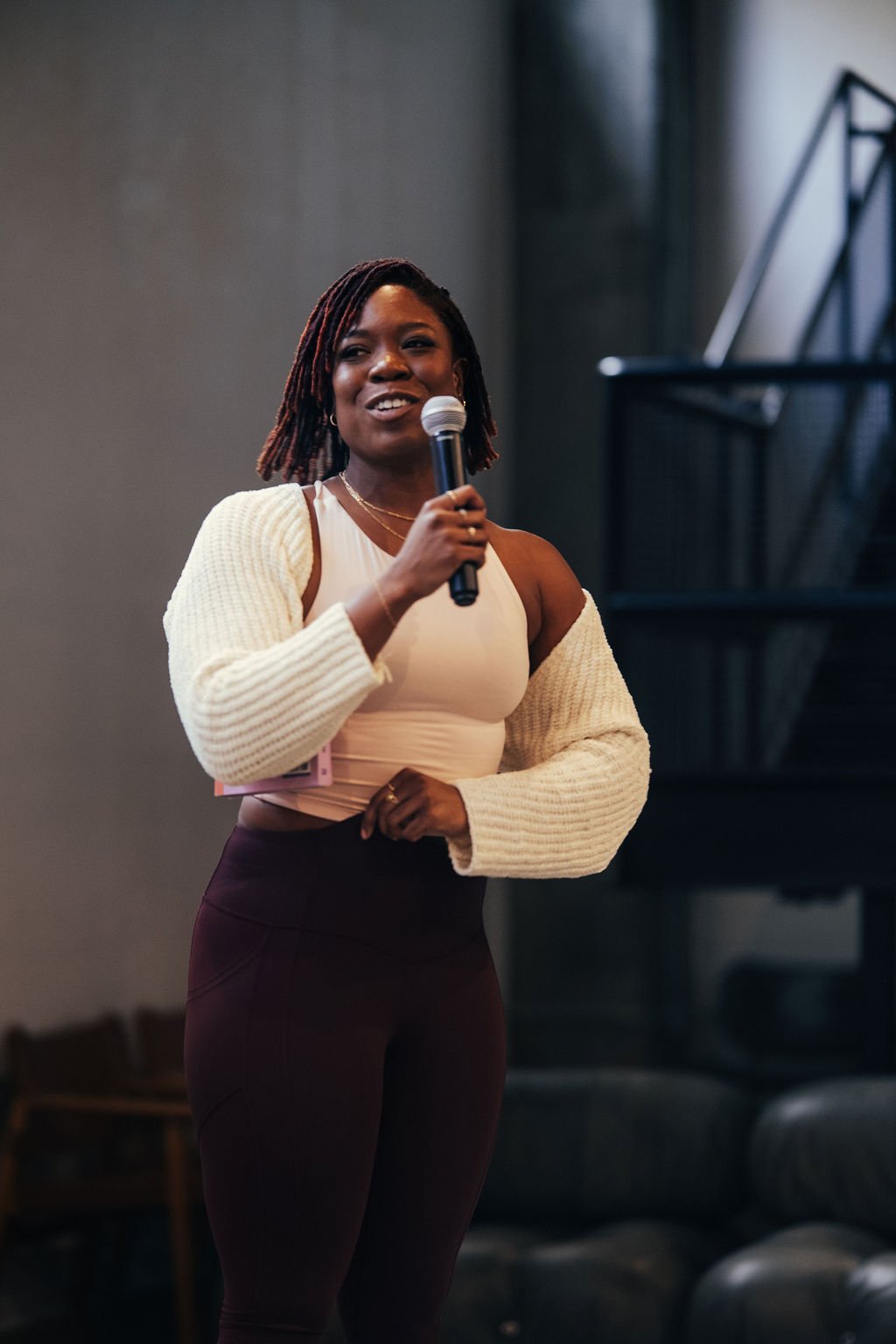 A woman speaking into a microphone at an indoor event.