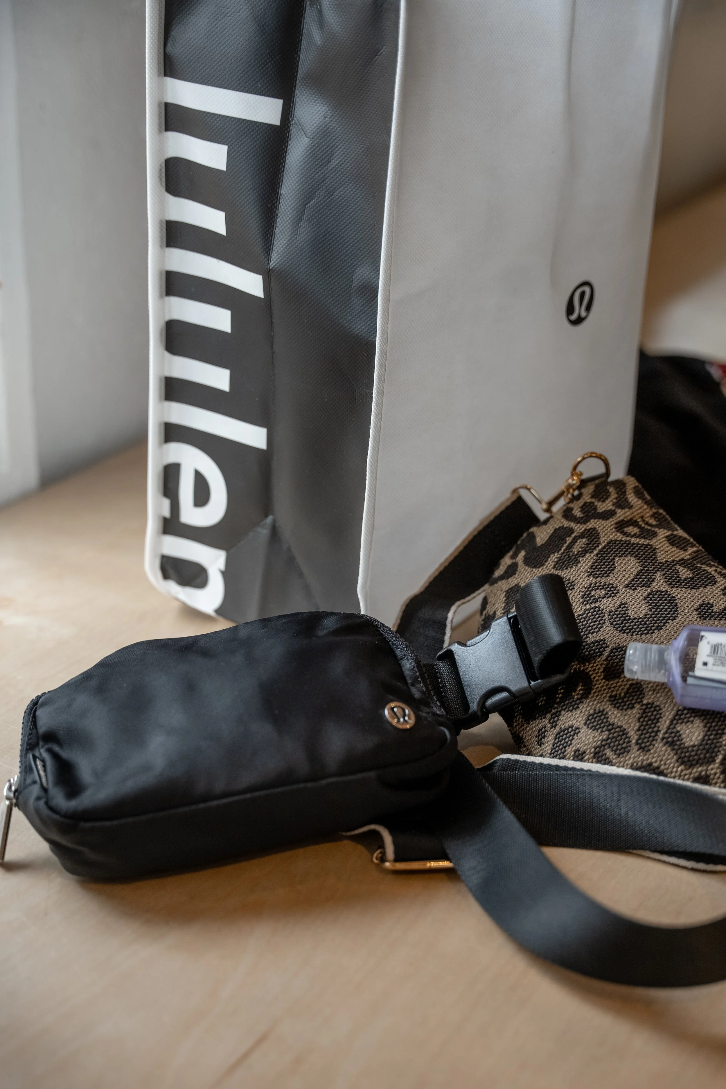 Travel bags and a shopping bag on a wooden surface.