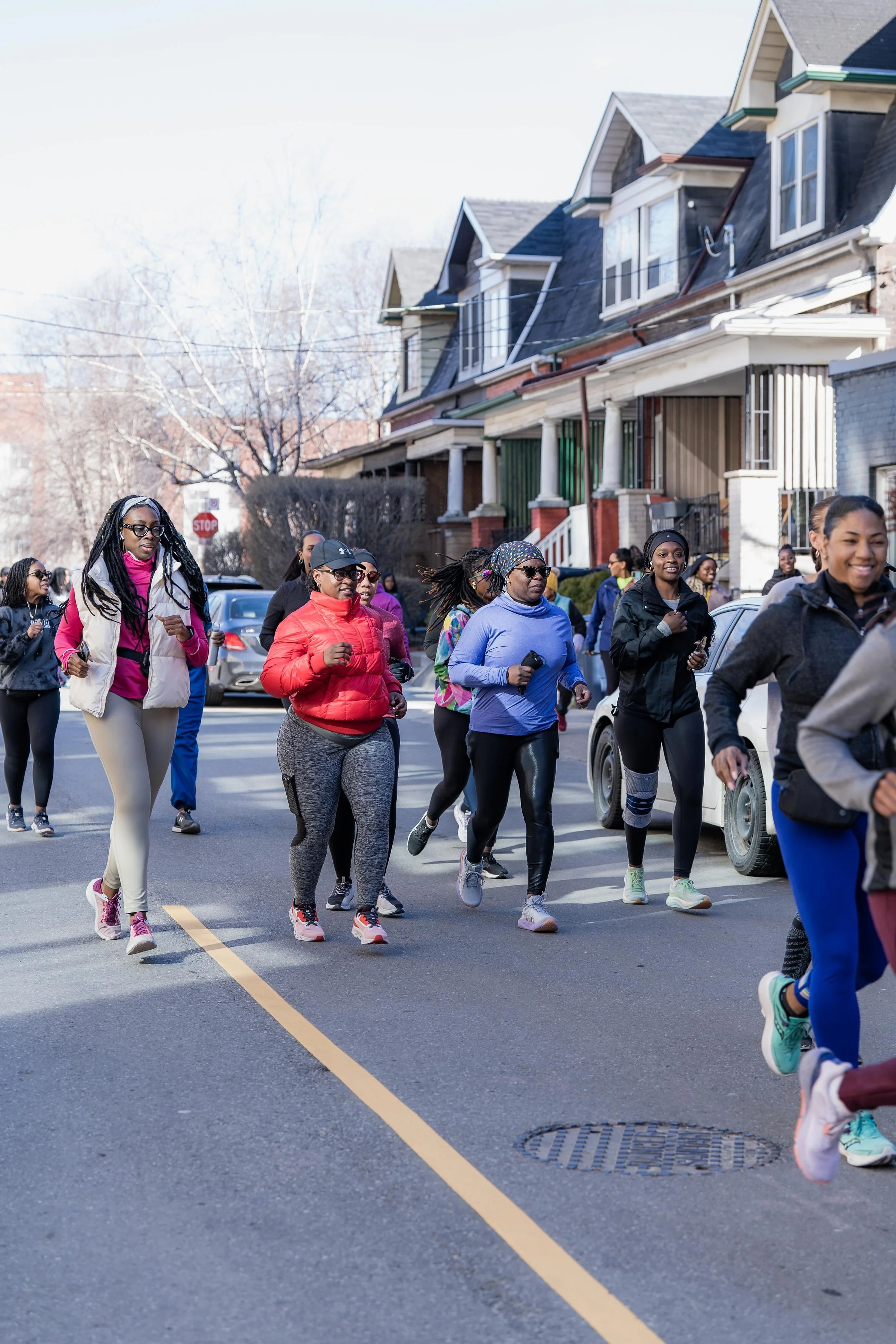 Group of women and girls walking in a community outdoor event on a street in a neighborhood with houses.