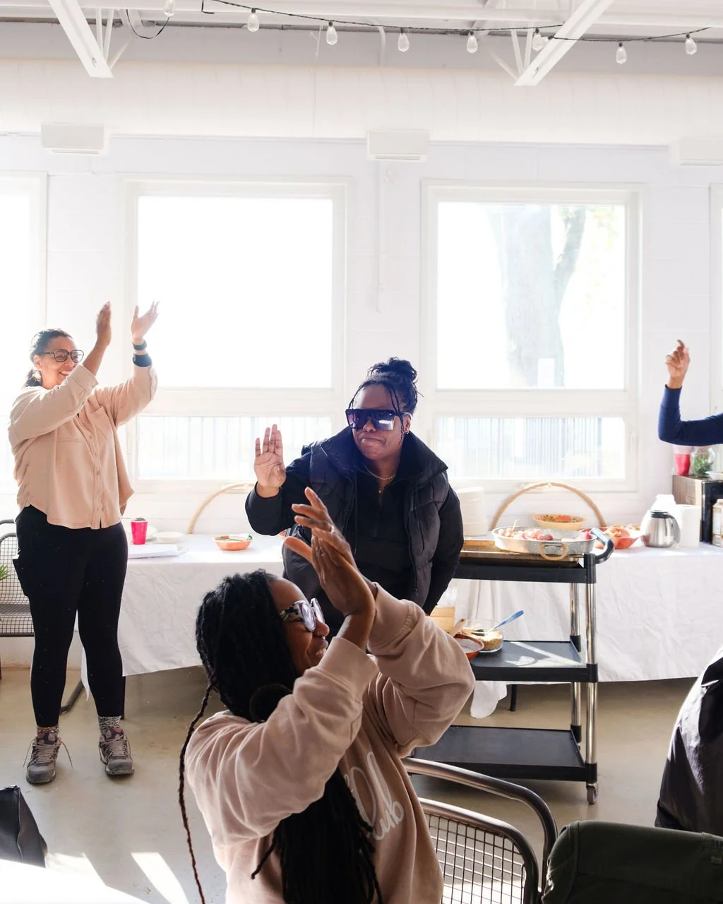 People dancing and enjoying themselves indoors in a bright, casual setting with large windows.