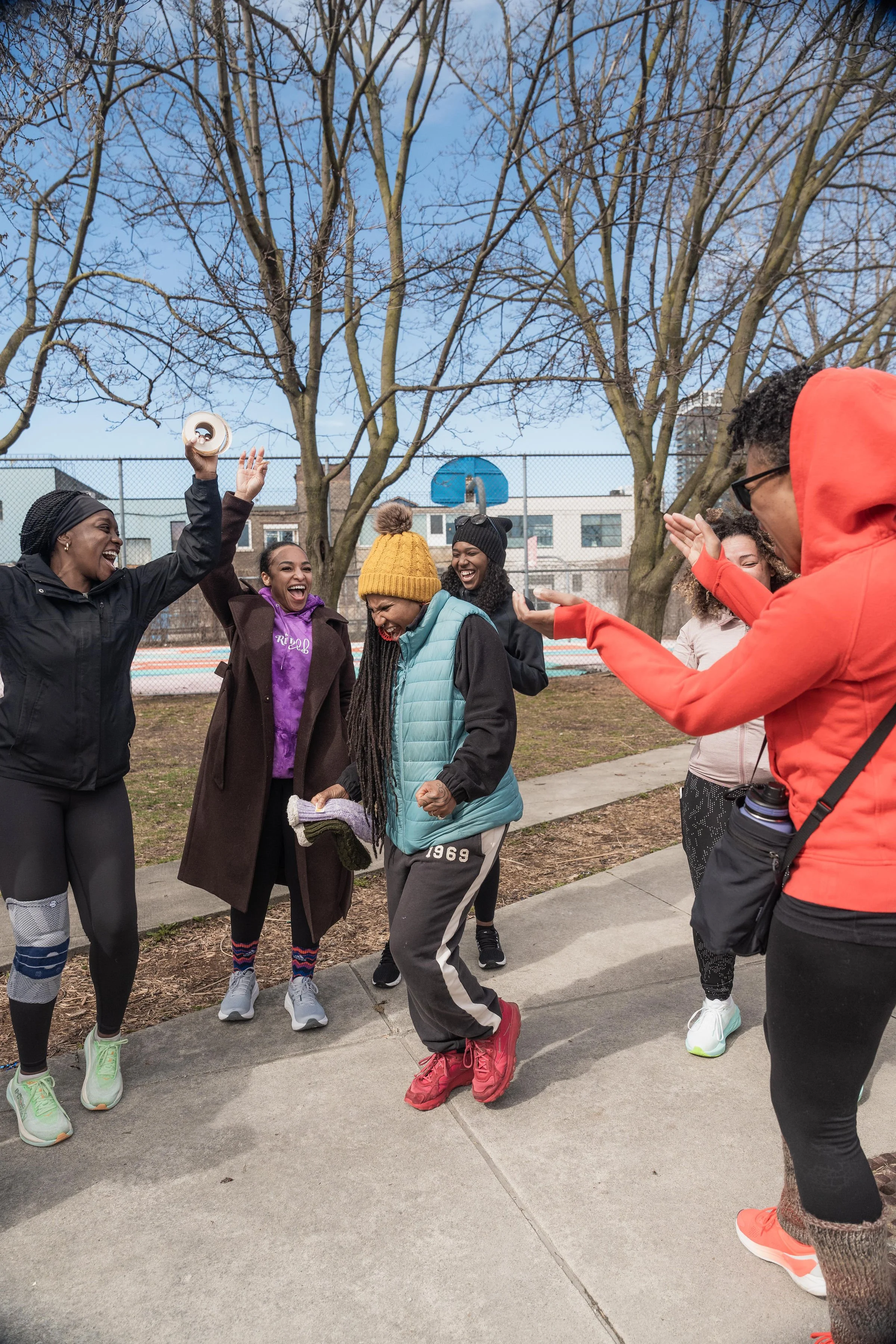 Group of women outdoors celebrating and having fun, with one woman dancing and others clapping.