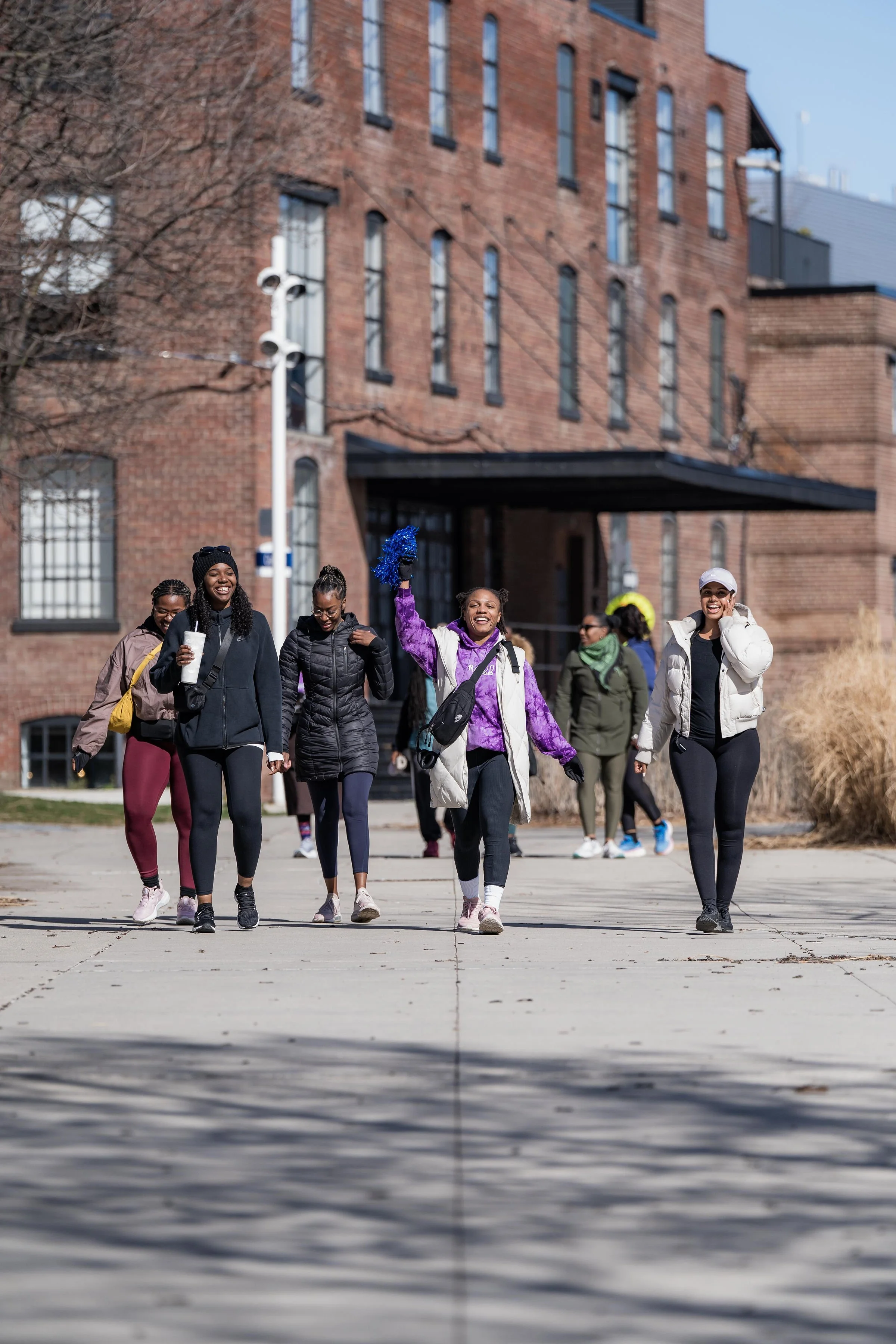 A group of women walking outdoors on a sunny day, smiling and enjoying each other's company.