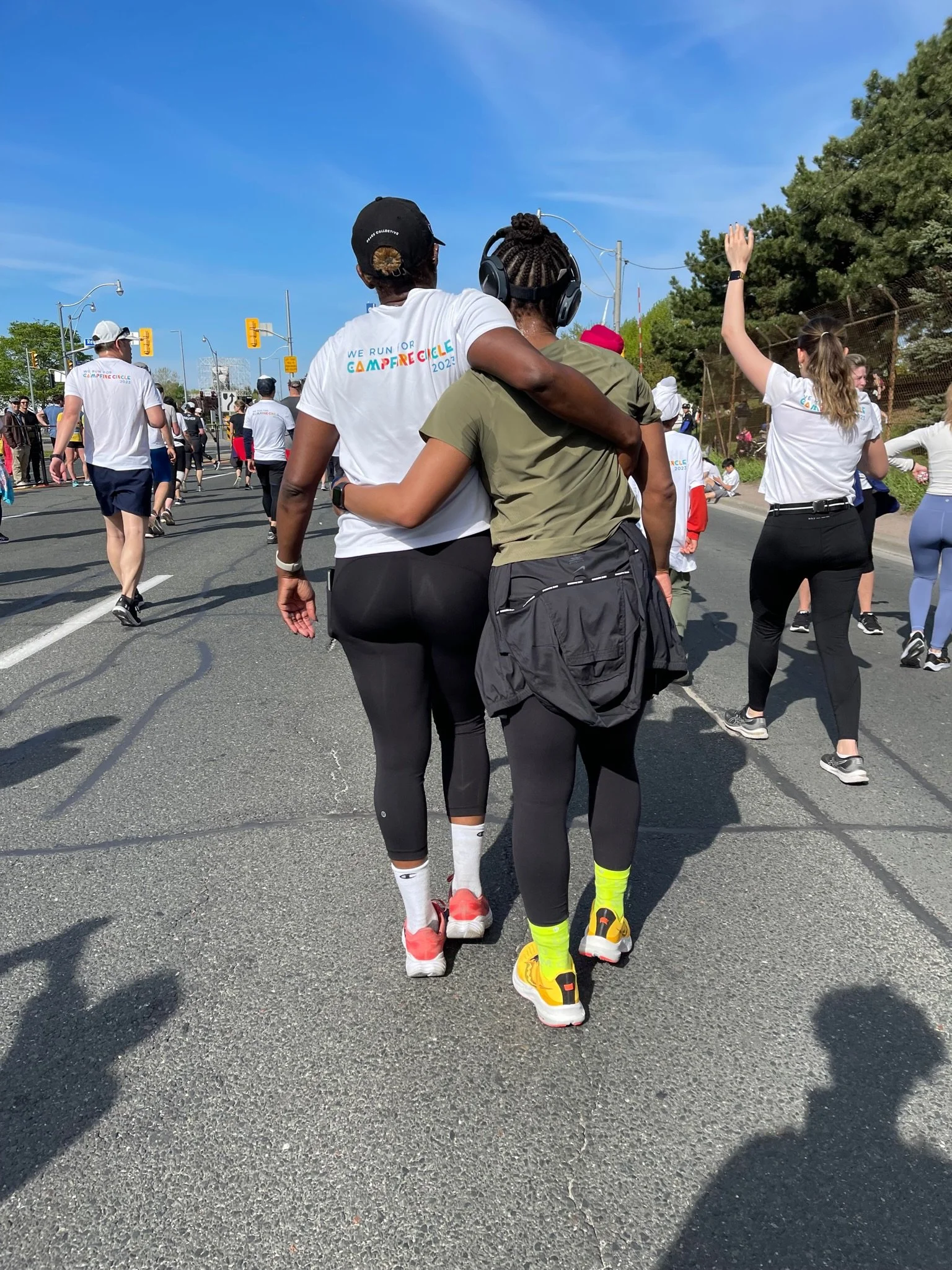Two Black women walking side by side after a race, with one woman’s arm around the other's shoulders, embracing. 