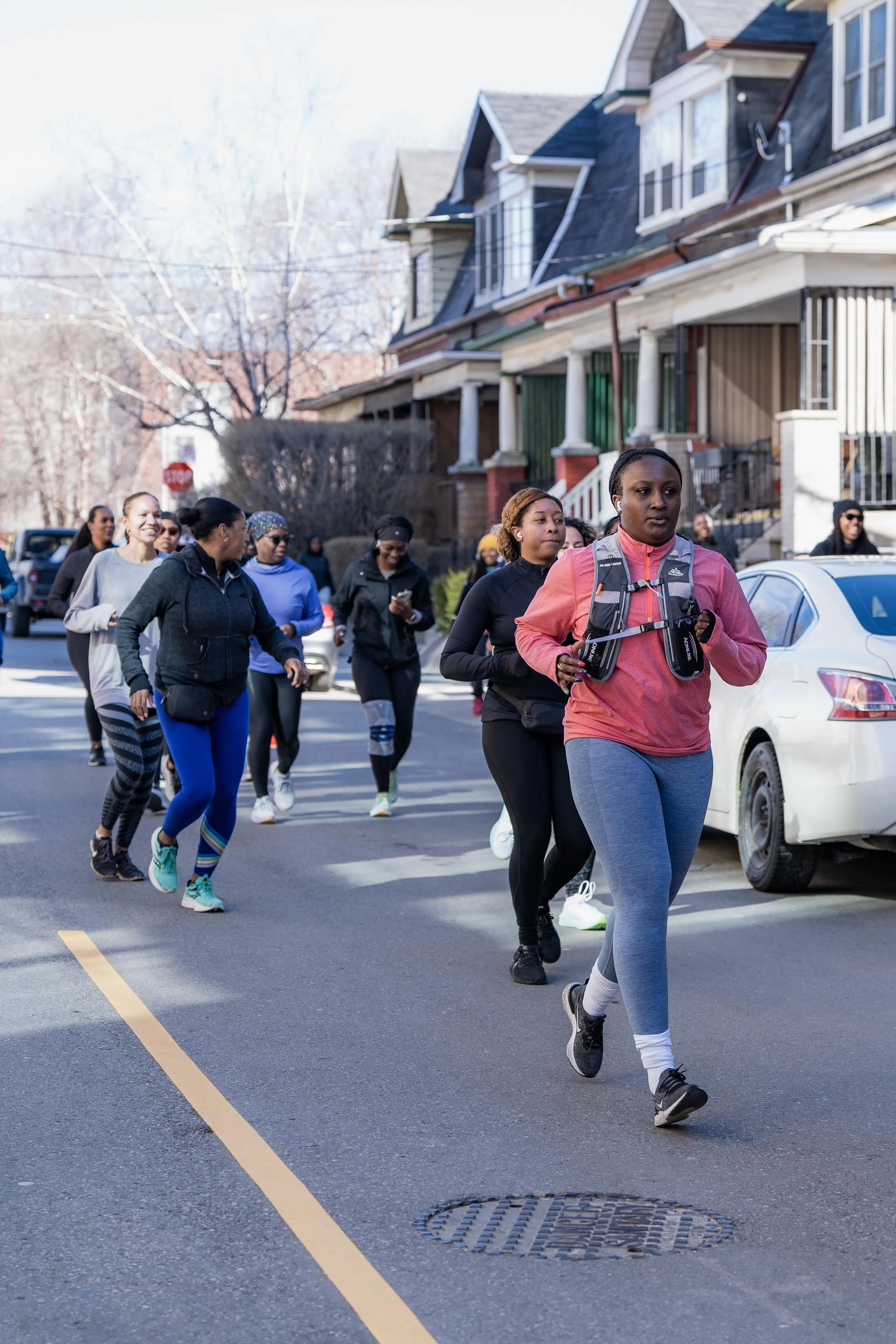Group of women jogging together on a city street, with residential houses in the background.