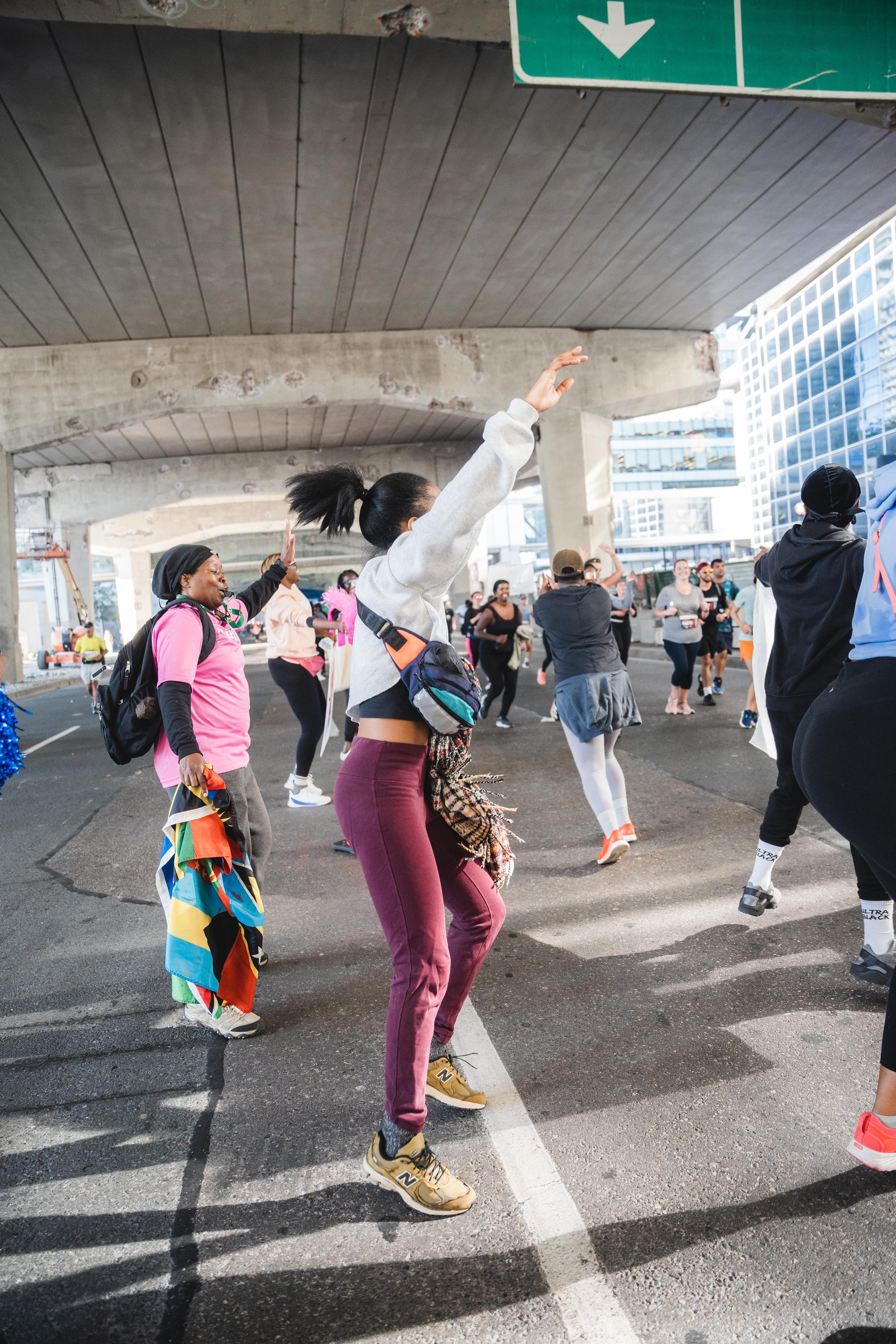 People participating in a dance or fitness event under an overpass in an urban area.