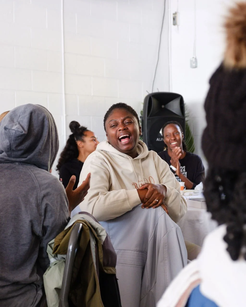 A group of diverse women sitting together in a room, engaging in a discussion or sharing emotional moments, with one woman in the center crying.