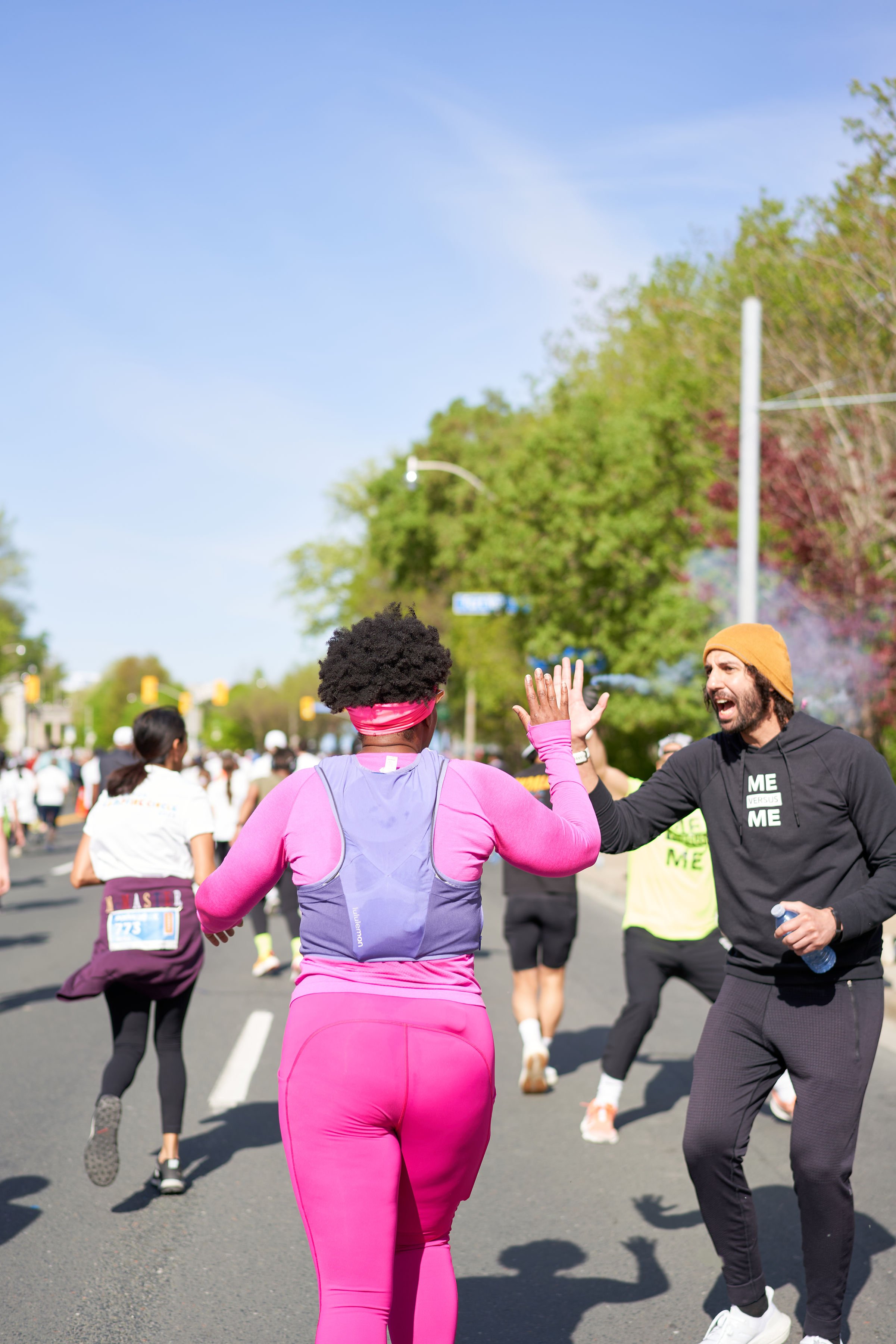 Black runners high-fiving during a race on a sunny day.