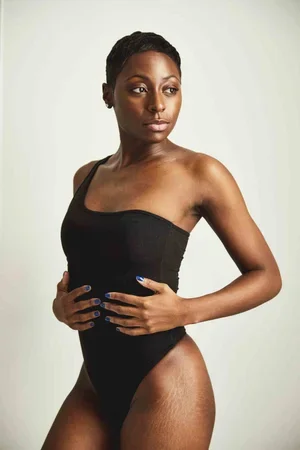 Model wearing a black one-shoulder swimsuit against a light grey background.