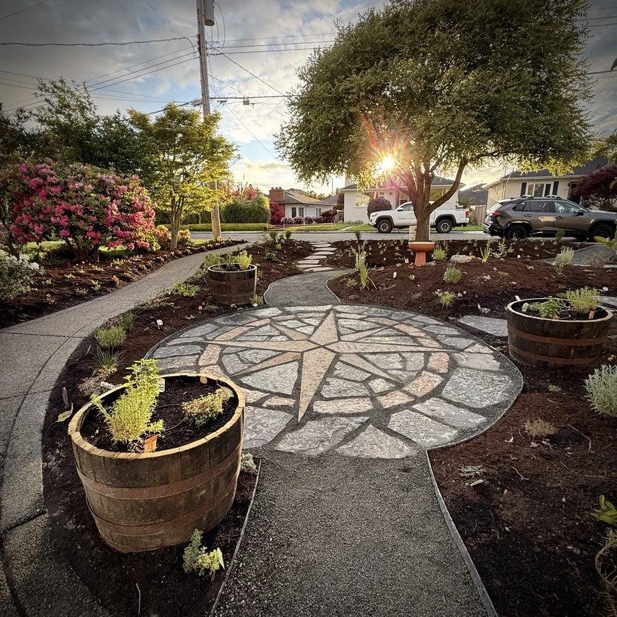 Stone compass patio surrounded by perennial garden beds in the evening light