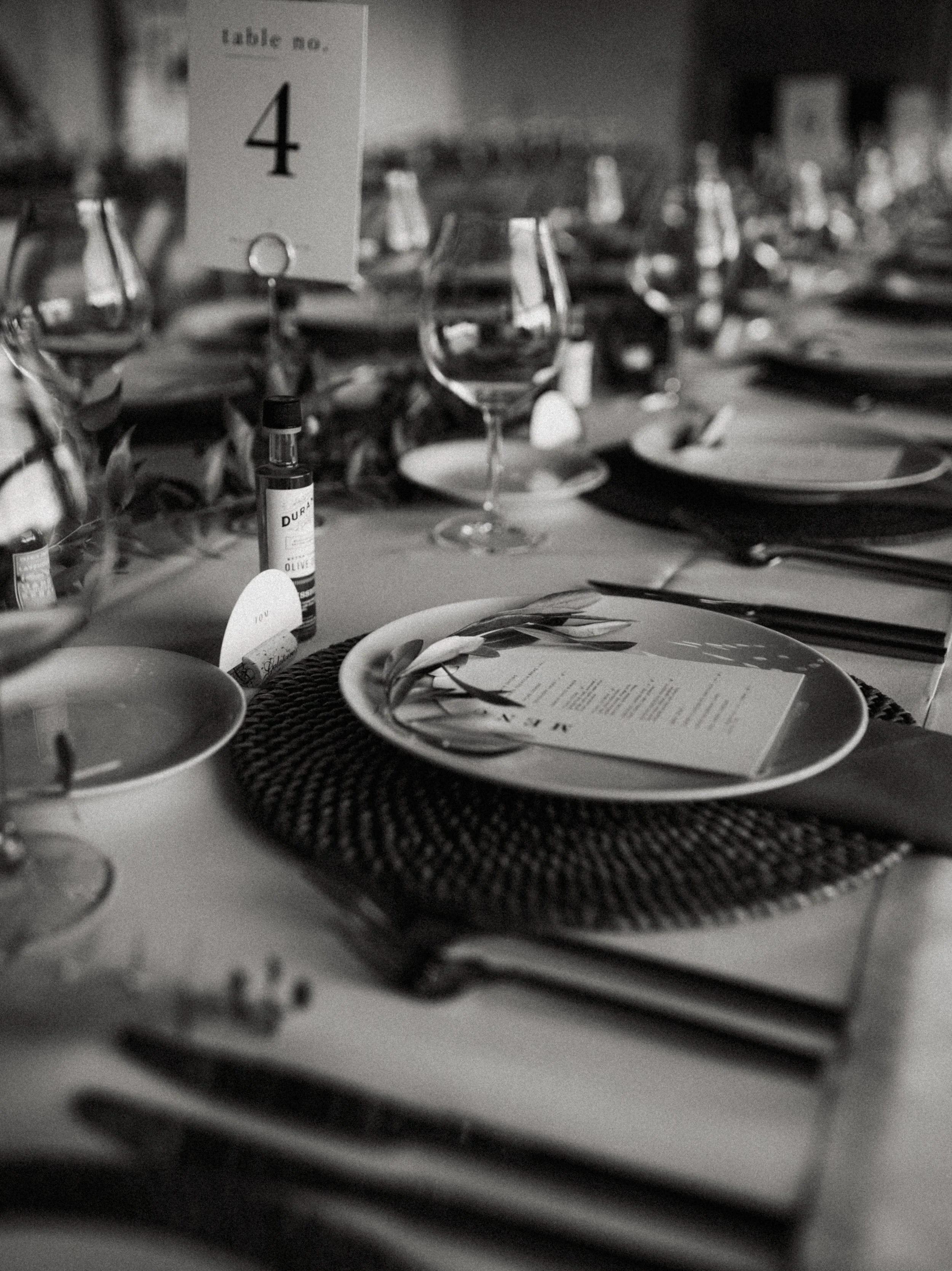 Table setting for a formal dinner with plates, glasses, cutlery, a menu, and a table number sign reading '4' in black and white.
A beautiful wedding at a vineyard in california 