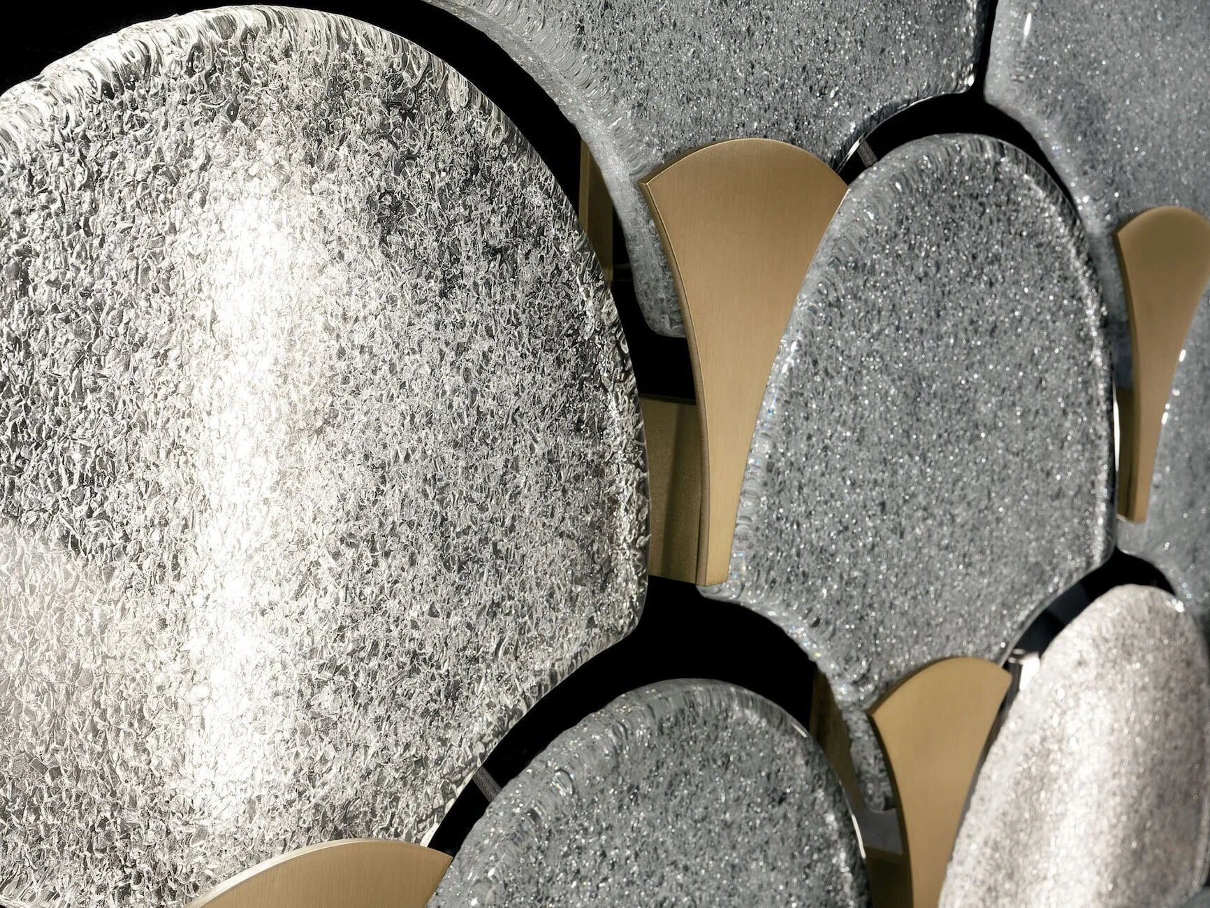 Close-up of round tables with silver, glittery, textured surfaces and gold-champagne colored chairs with black frames arranged around them.