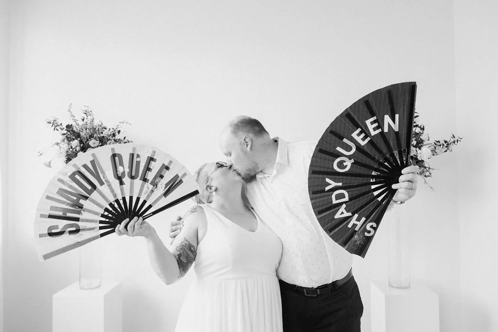 Black an white photo of newlyweds kissing while holding out fans saying shady queen I Elopement in Kitchener Waterloo by CK &amp; Co Events