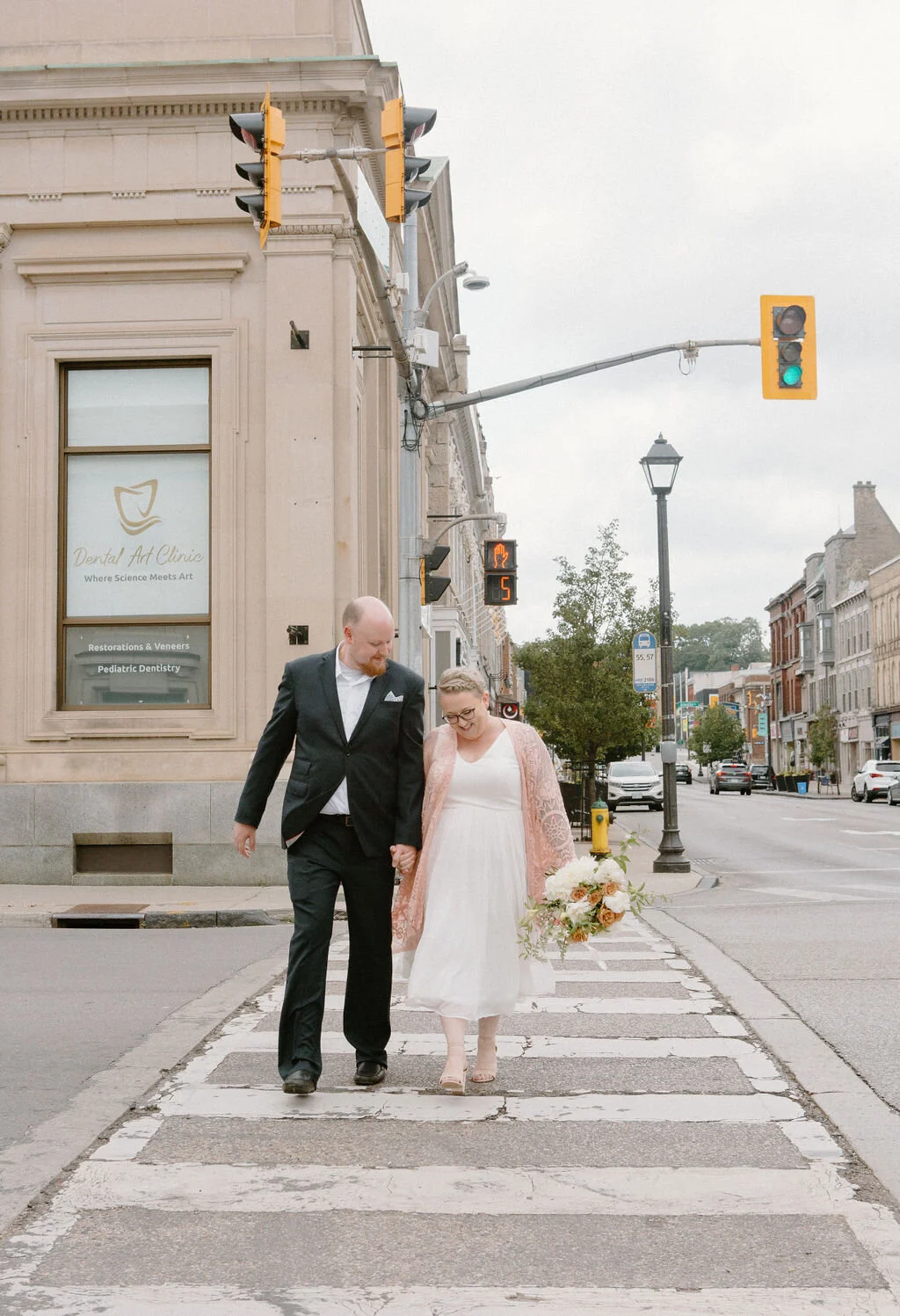 Bride and groom crossing the road holding hands in their wedding attire I Elopement in Kitchener Waterloo by CK &amp; Co Events
