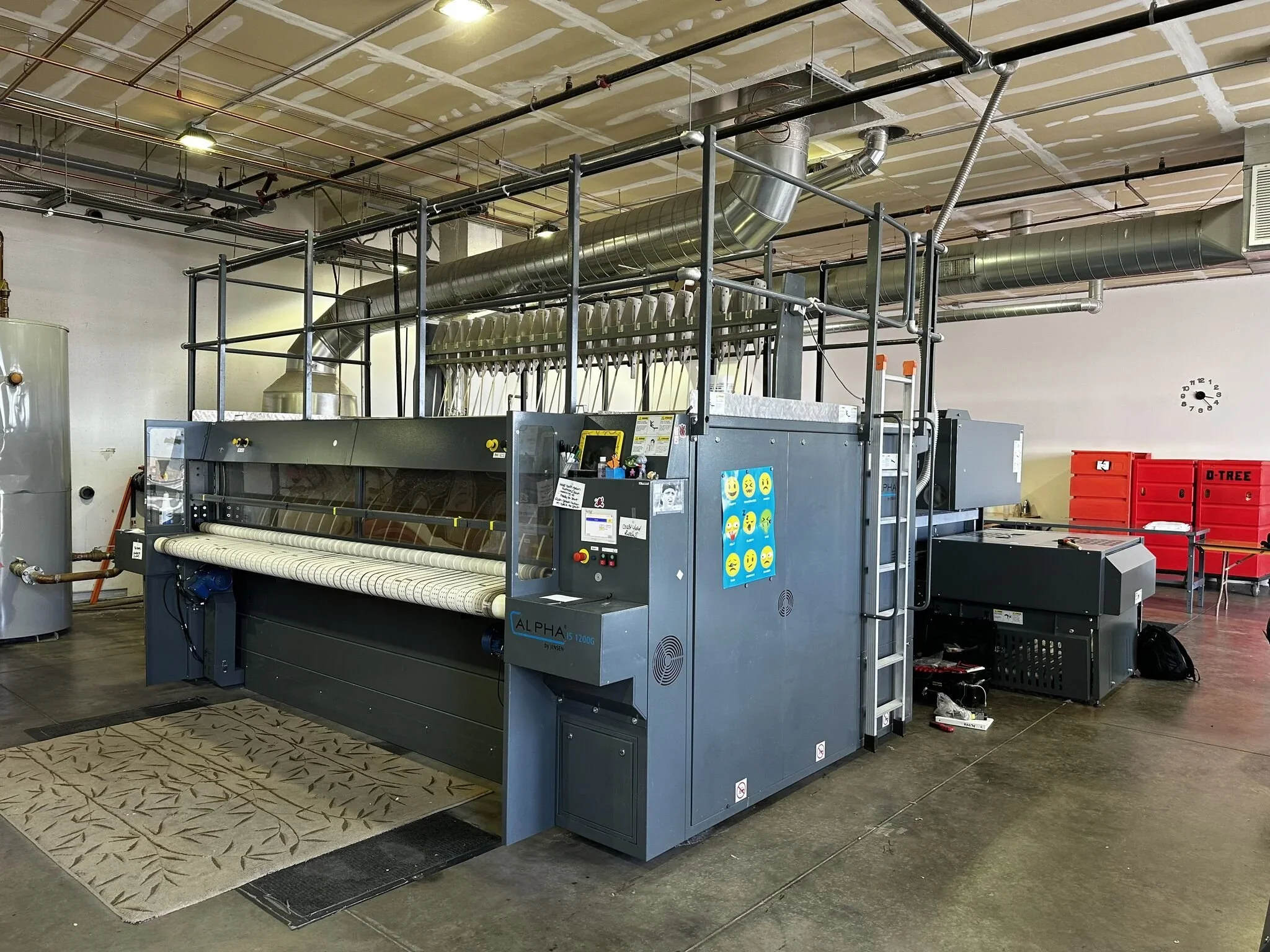 Large industrial dye sublimation printer in a workshop, with red storage boxes in the background.
