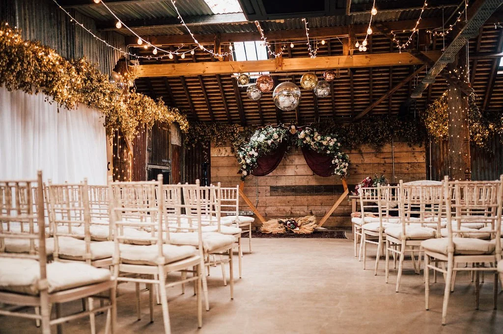 Rustic winter wedding venue decorated with floral arch, warm festoon lighting, hanging decorations in a charming barn setting Oak Tree Barn Weddings Tonbridge