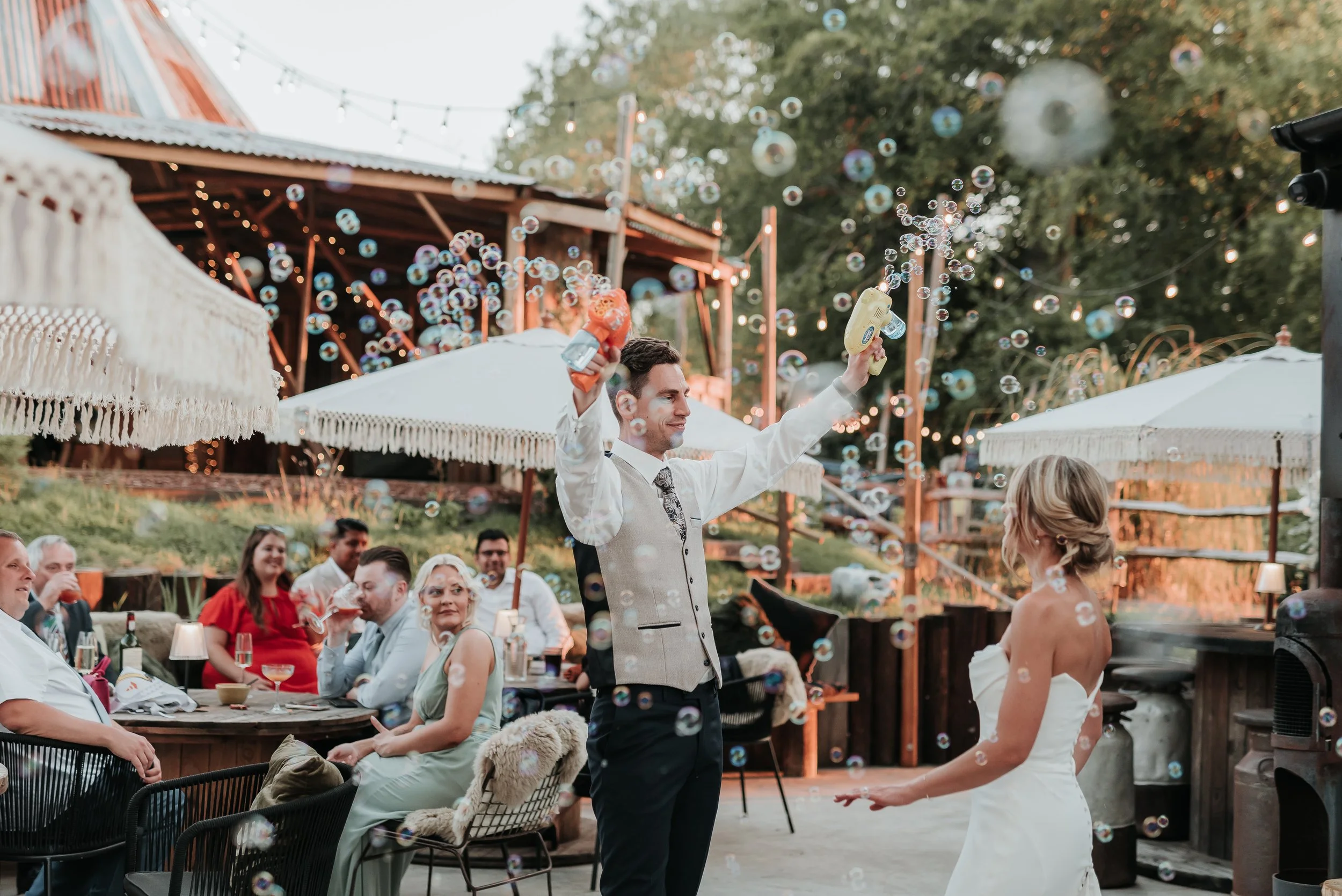 Newly wed celebrating with family and bubble guns Oak Tree Barn Weddings Tonbridge