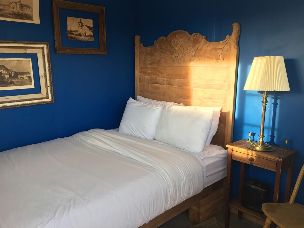 bedroom-with-blue-walls-wooden-bed-hanging-frame-art