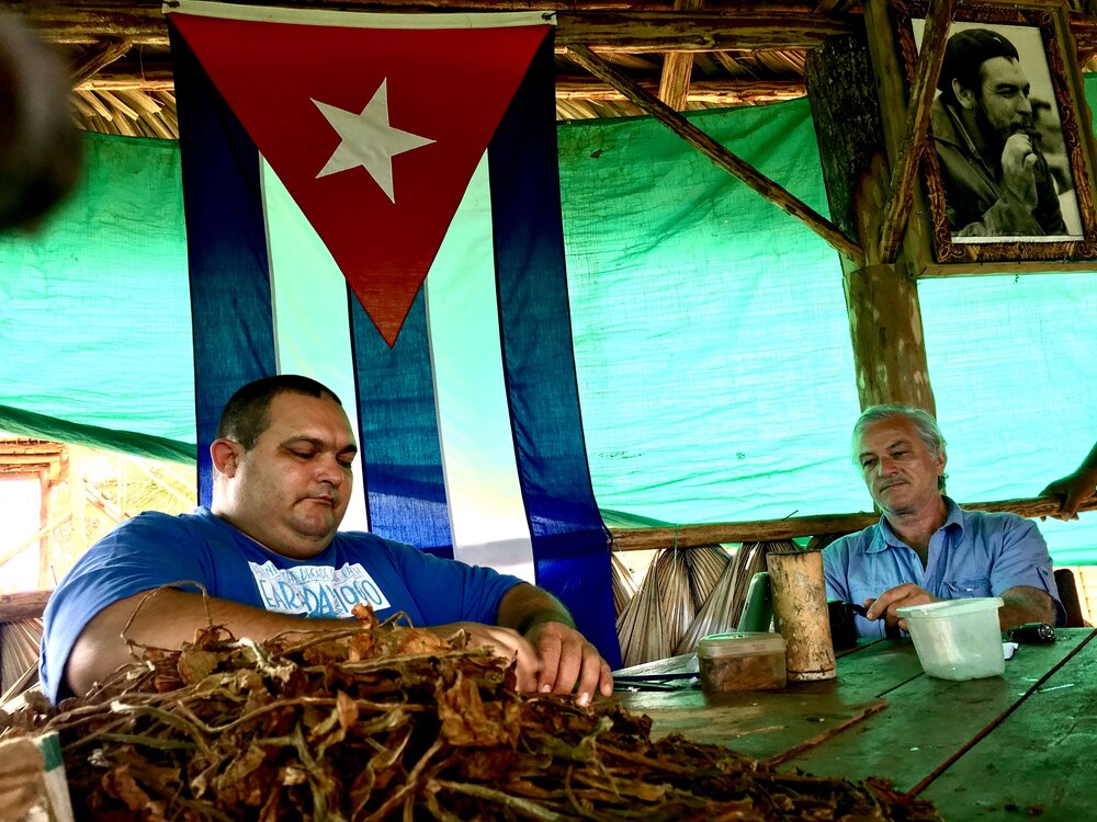 Man-rolling-cuban-cigars-with-cuba-flag