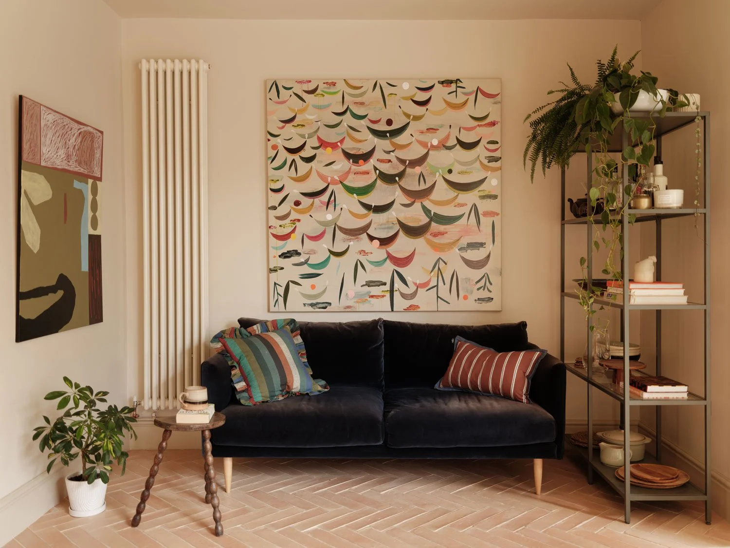 A kitchen lounge area in a contemporary kitchen in Knowle, Bristol. A blue velvet sofa is contrasted against light beige walls and large colourful paintings on the walls