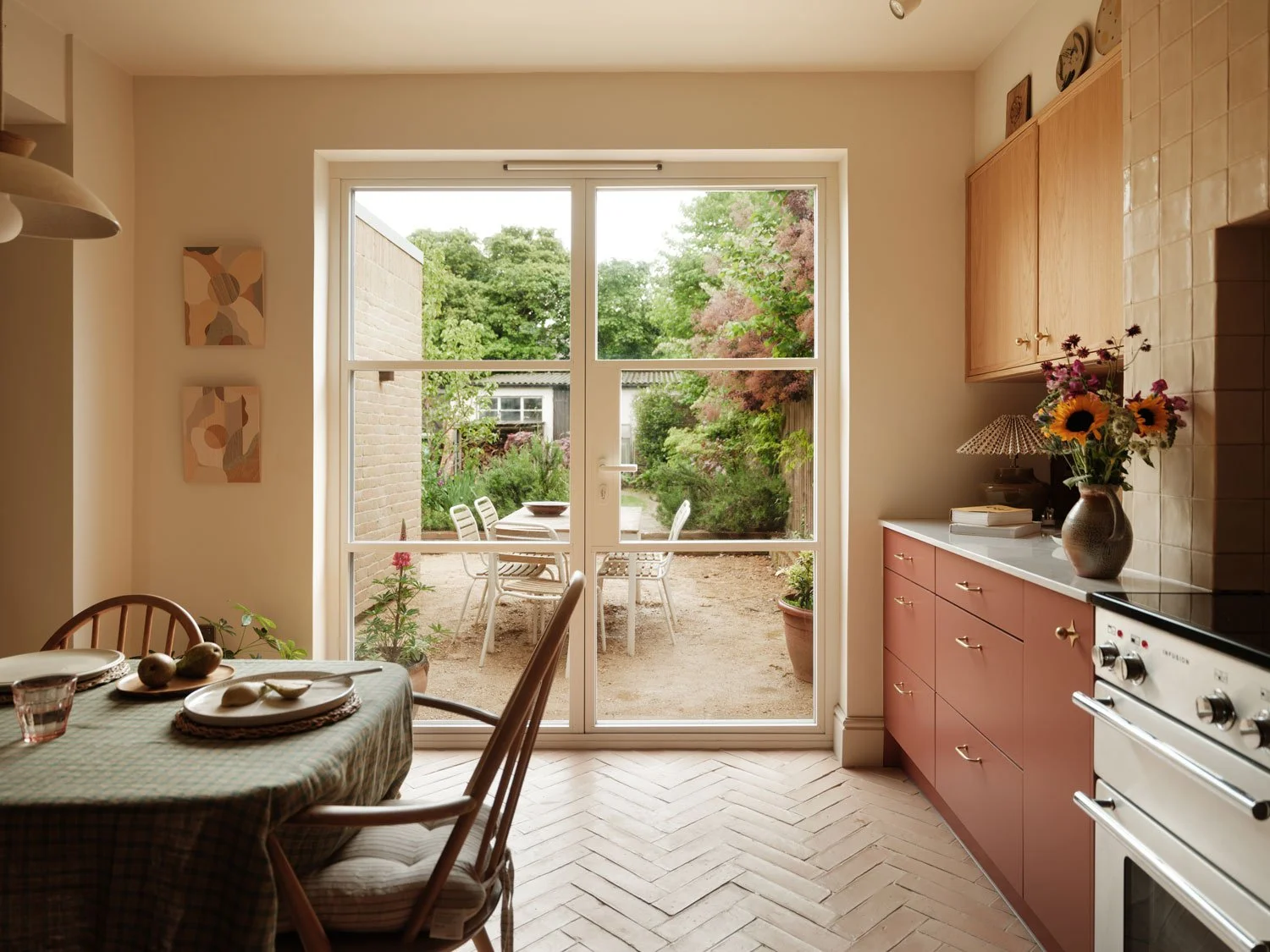 A contemporary characterful kitchen design in Knowle, Bristol with warm terracotta floor tiles and views out on to a leafy garden