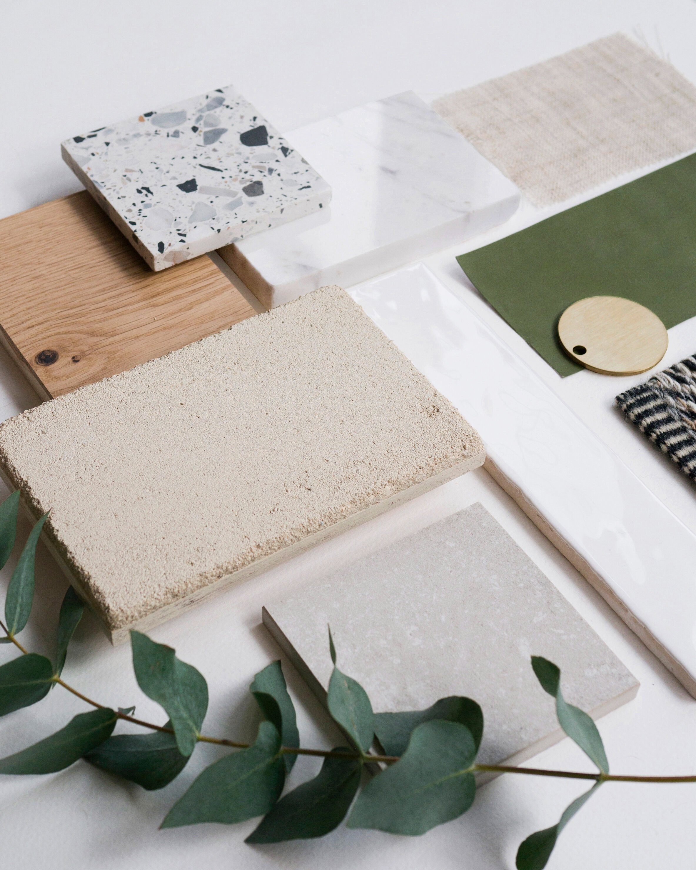 Material board in warm neutral tones. Natural finishes such as textural plaster wall finish, marble and oak