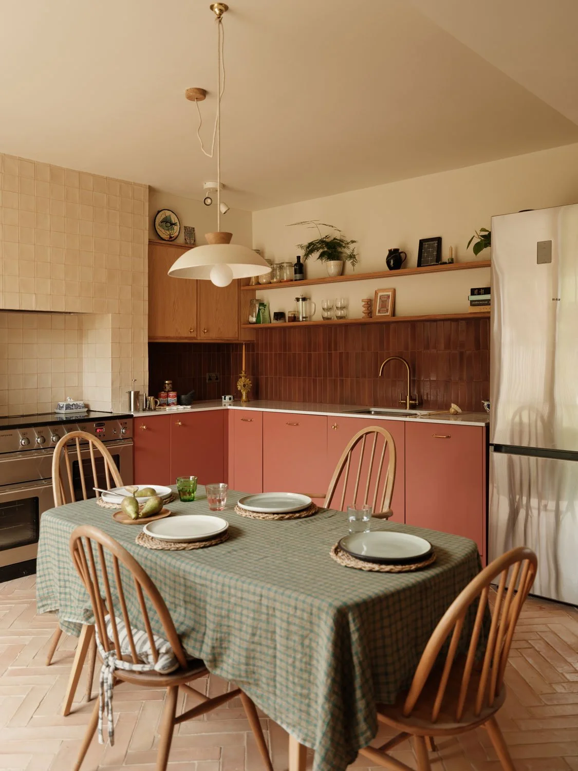 A contemporary kitchen design in Knowle, Bristol with moody red painted and oak cabinetry. Brass cabinet pulls add warmth and character. A large stainless steel range is the focal point of the kitchen