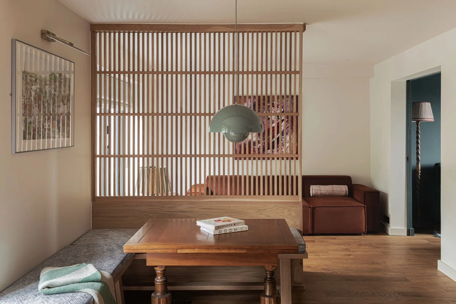 Bespoke oak slatted screen and bench seating divides the open plan dining and living space. A colourful pendnat hangs low over  the dining table