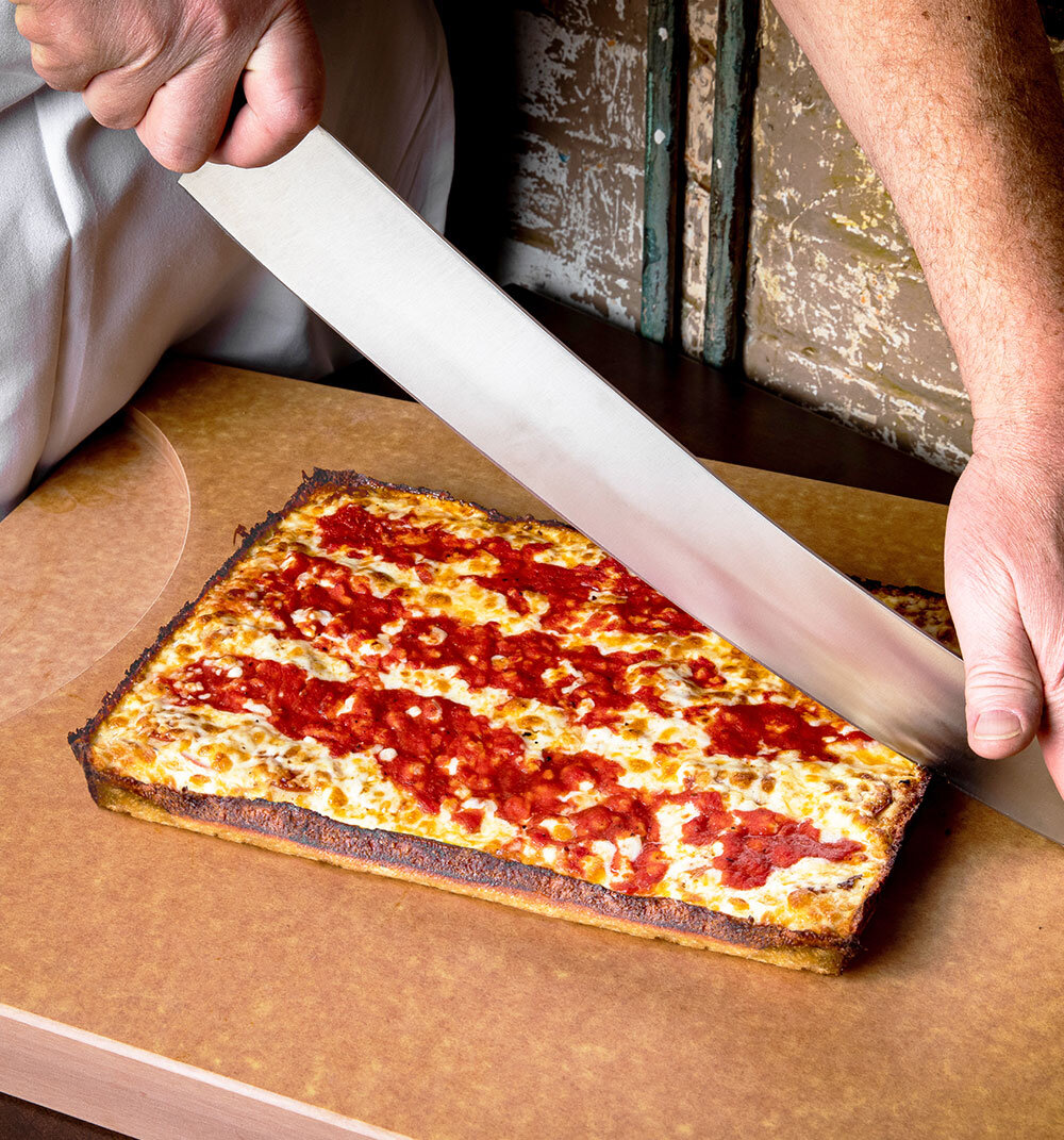 A Detroit-Style pizza from Buddy's Pizza in Detroit, Michigan being sliced.