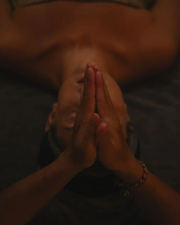 Person receiving a Reiki or massage treatment with hands pressed together on the forehead.