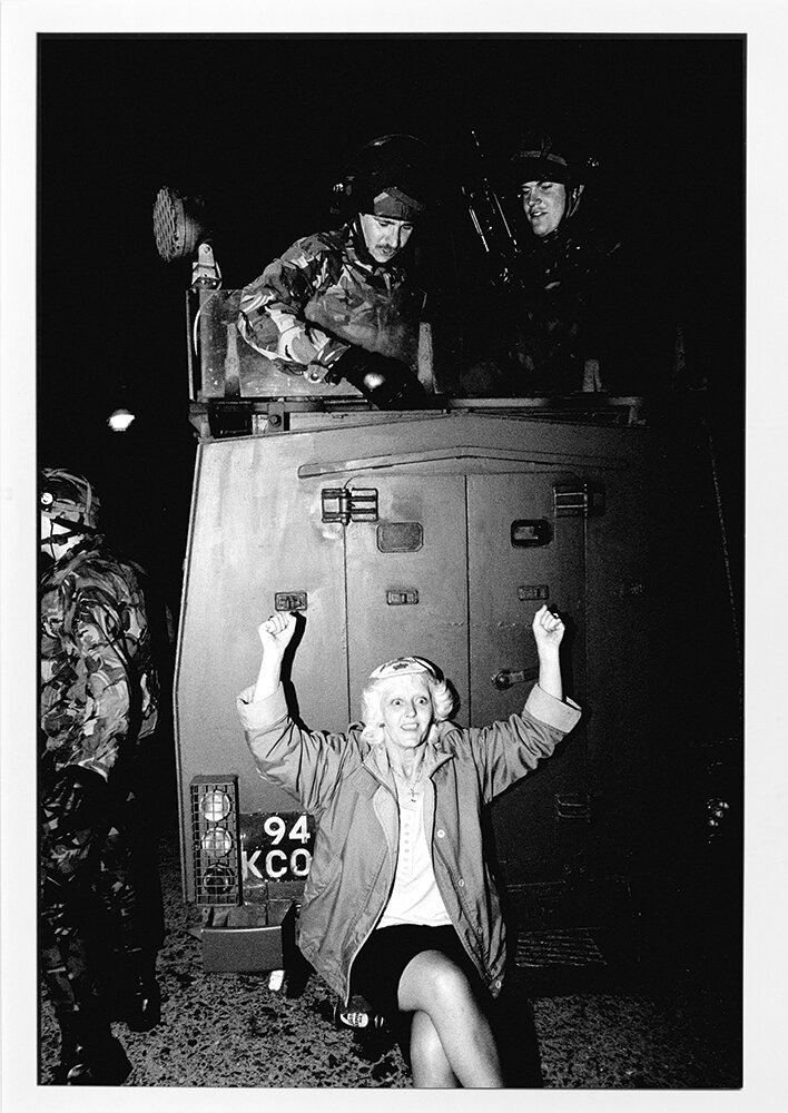  A woman, sitting on a military vehicle, cheers on sitting on the "Eleventh Night" Bonfire ushering in the "Twelfth" festivities and celebrations of the Battle of the Boyne in Tiger's Bay, Belfast. 1990 