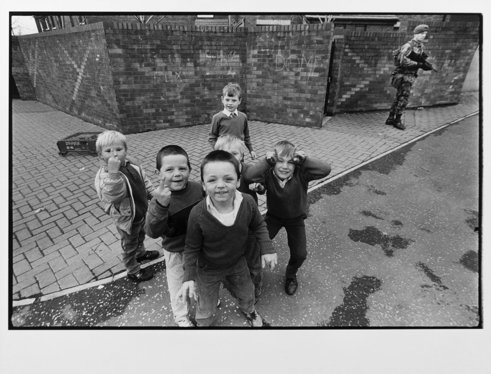  Catholic boys play while a British soldier stands in the background in Belfast, Northern Ireland. 1988 
