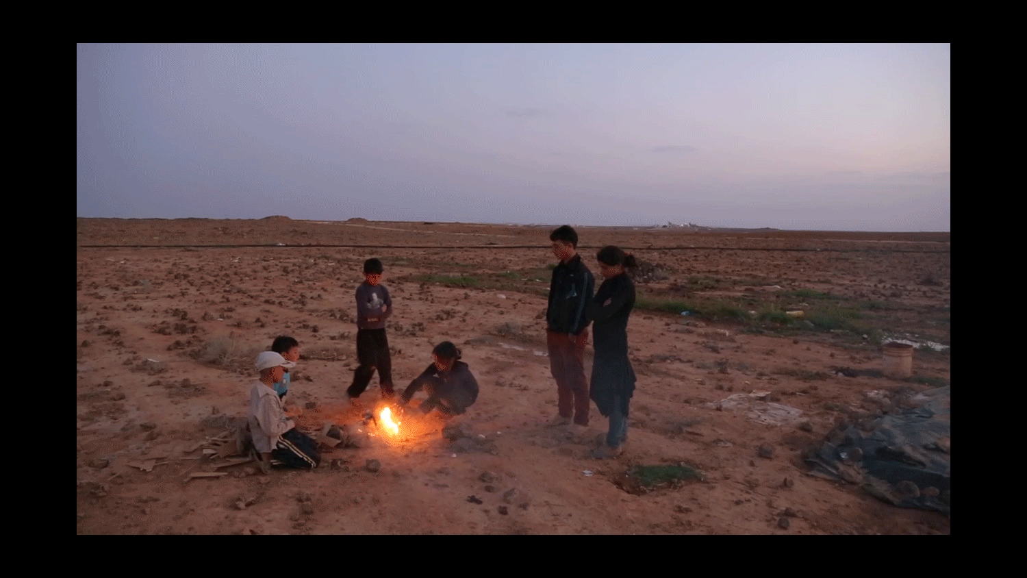  A refugee family gathers with fellow camp residents around a fire at dusk in the desert between the Syrian and Iraqi borders in Ereinbeh, Jordan. 2013 