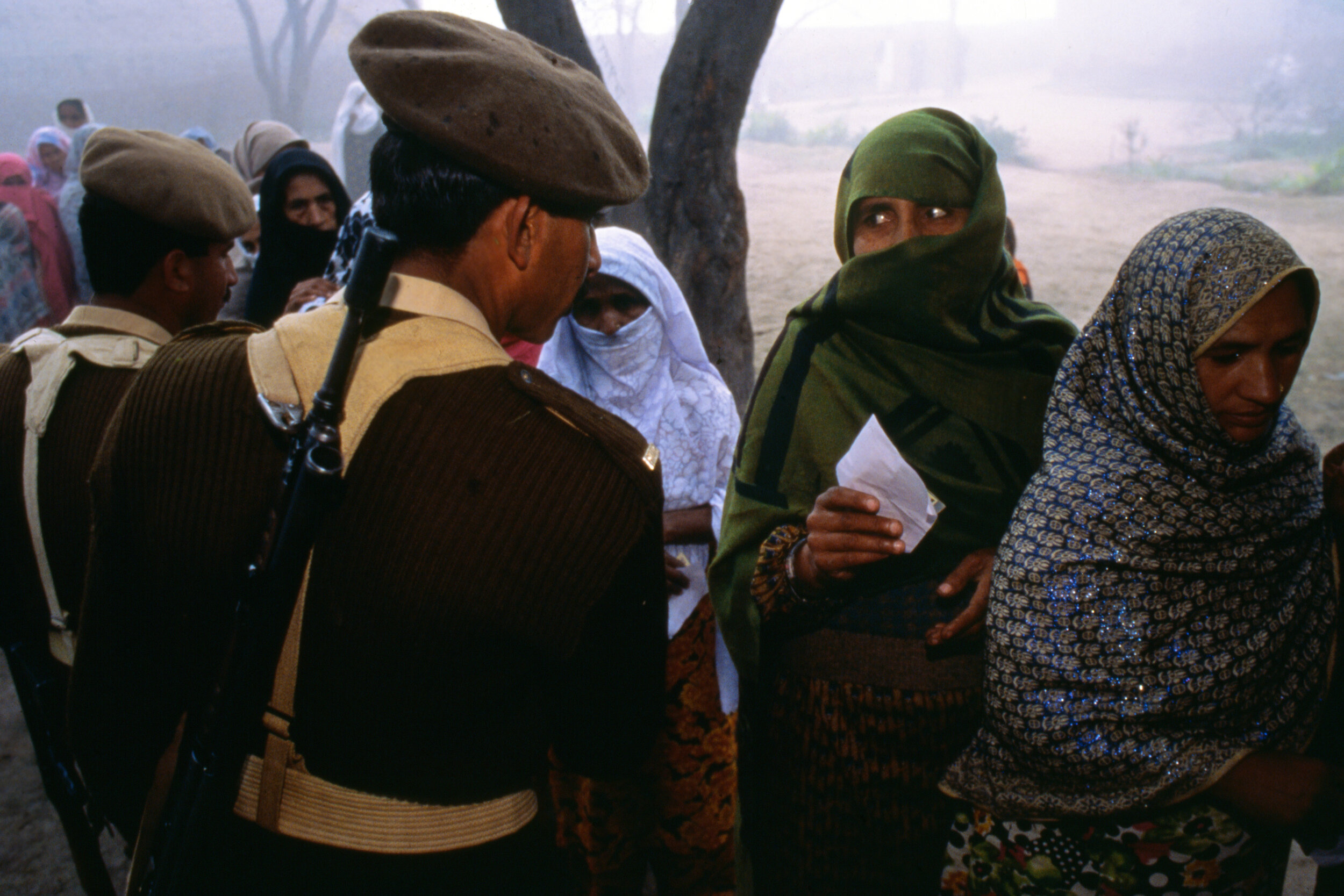  Women in the village of Sharqpur que up to cast their votes while soldiers guarantee a peaceful election day. Punjab, Pakistan. 1998 