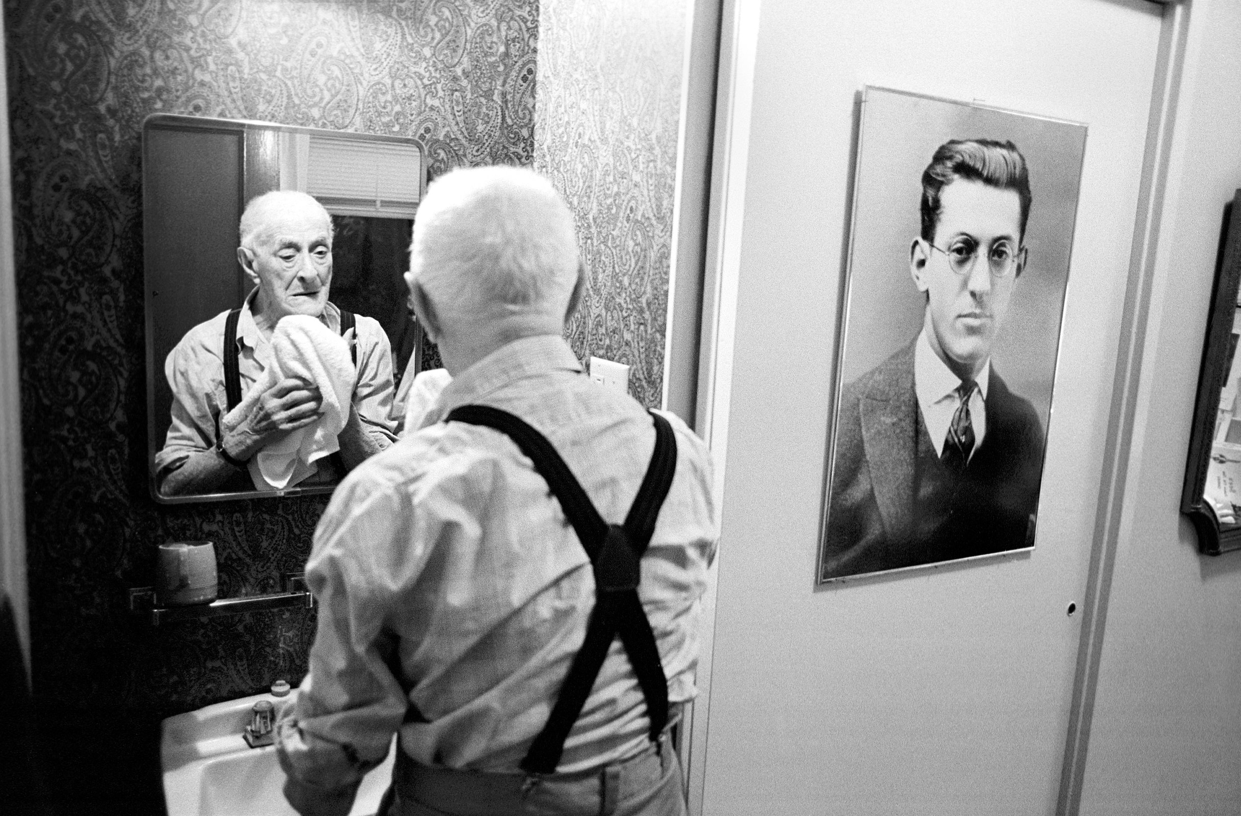  100-year-old Isaac Donner next to an old photograph of himself in the single-room occupancy hotel where he lives. 1999 