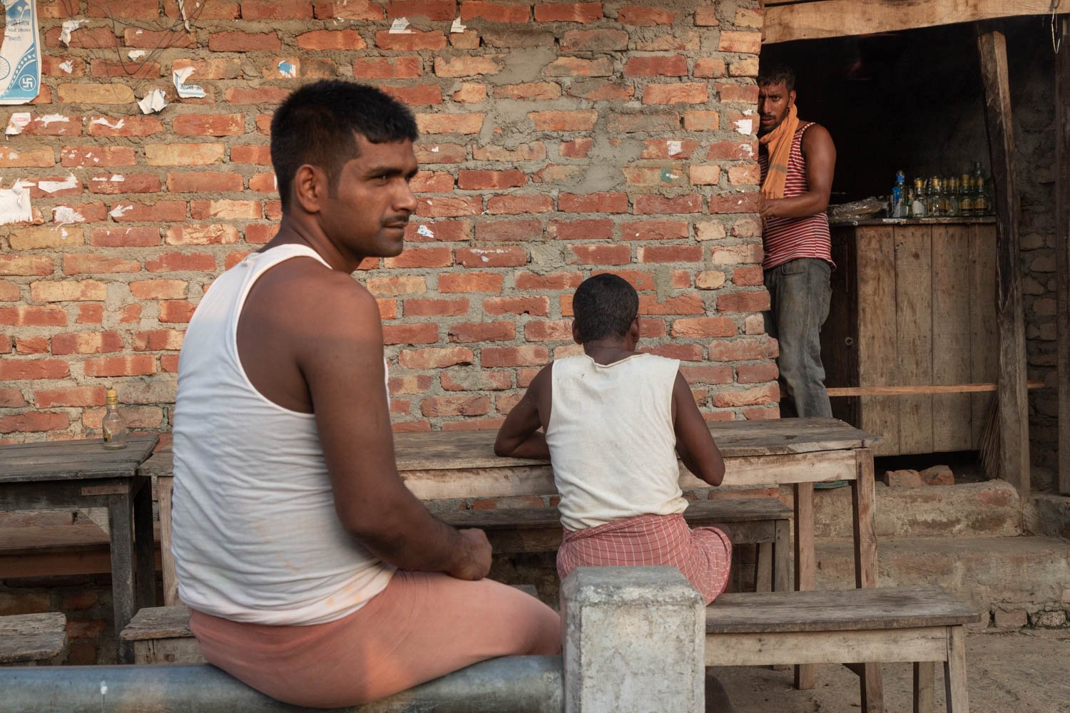  Nepali men sitting at a table in the village of Nagrain 9, in the Ghodhas District outside of Janakpur, Nepal on June 30, 2022.  In this village, like many of the agricultural lowlands of Nepal, 70%  of the young men have worked in Qatar and other G