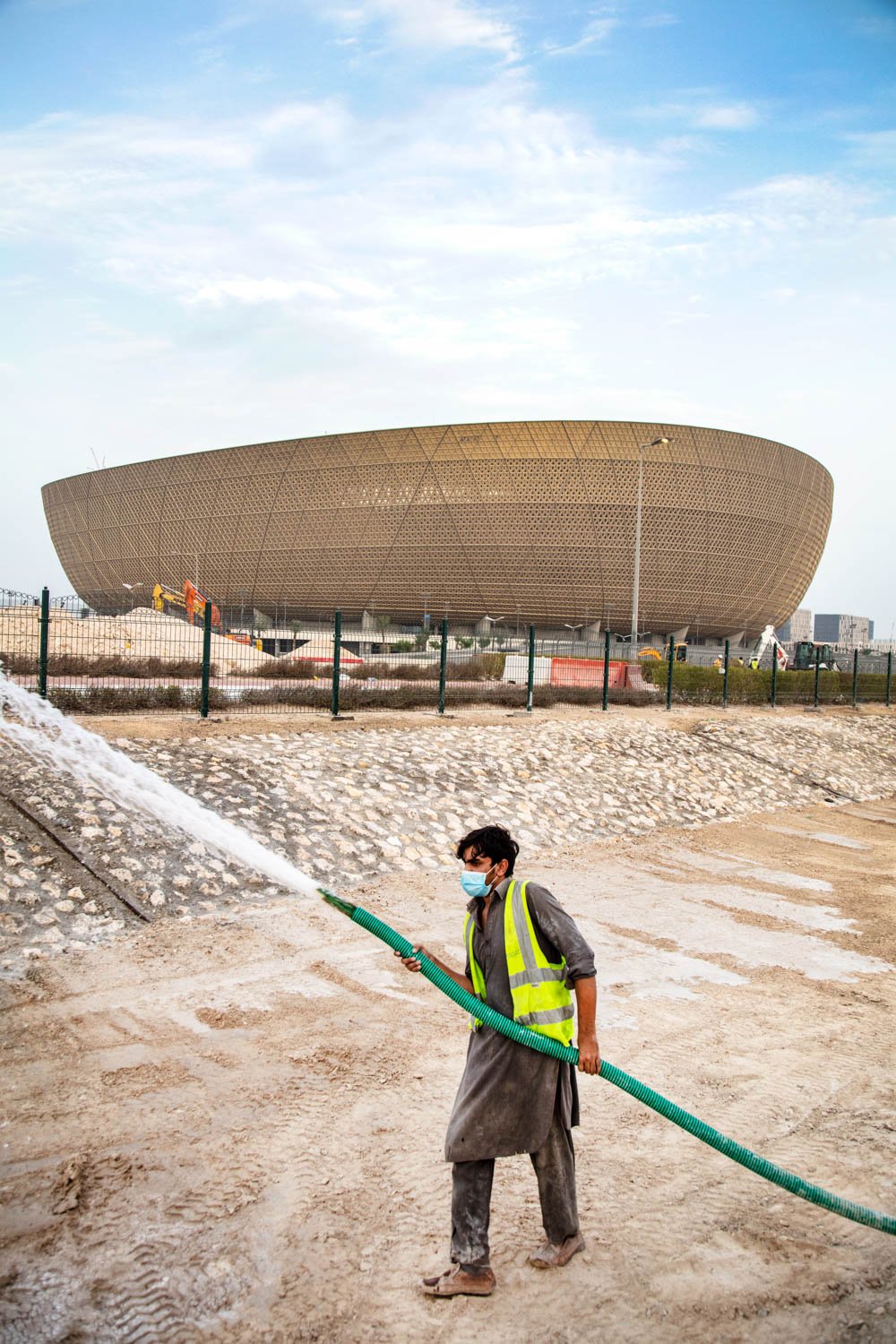  A worker puts finishing touches on the surrounding landscape of the main World Cup stadium in the Lusail area of Doha, Qatar on August 17, 2022. 
