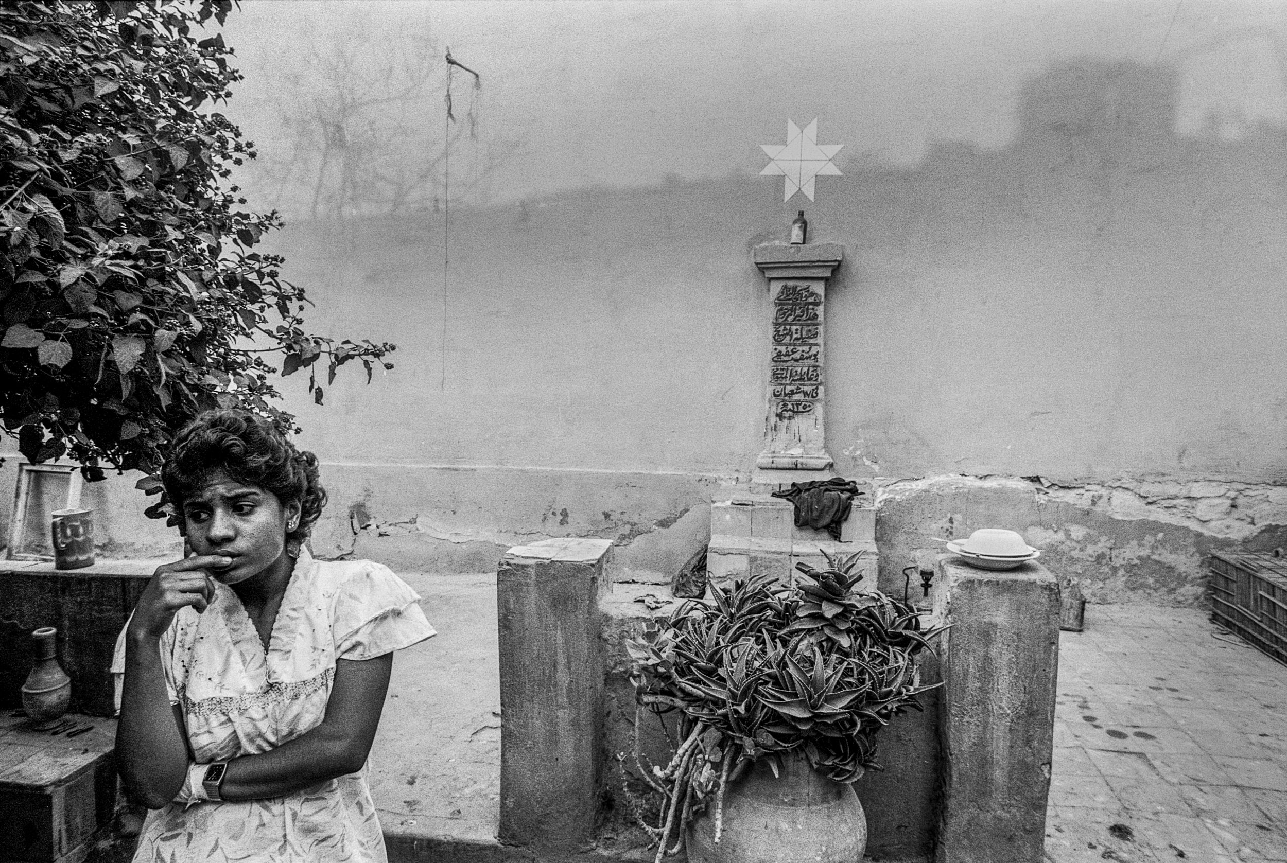  A young woman stands in front of a grave. 