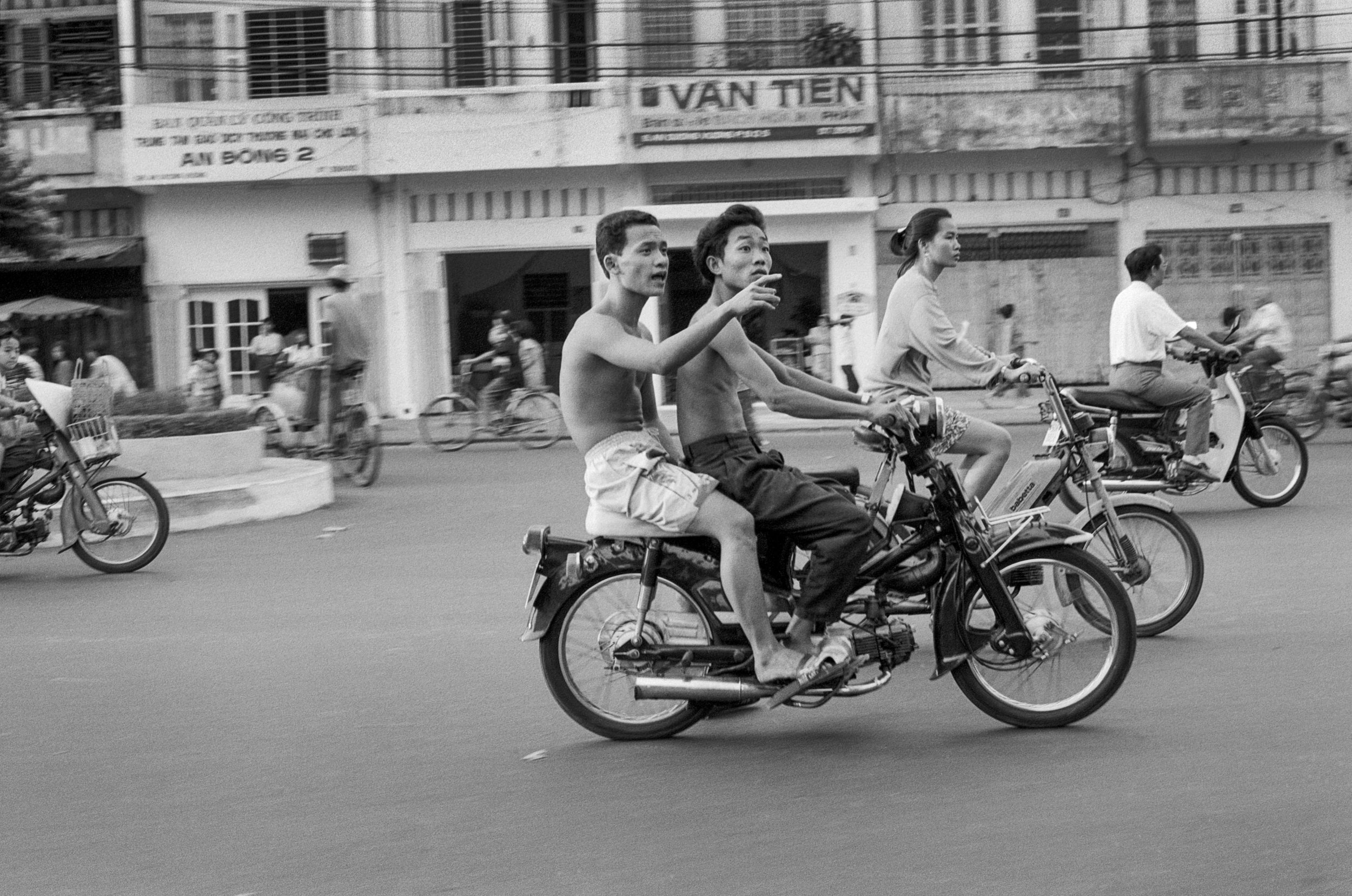  Vietnamese youth travel through the city shirtless on a motorbike. 