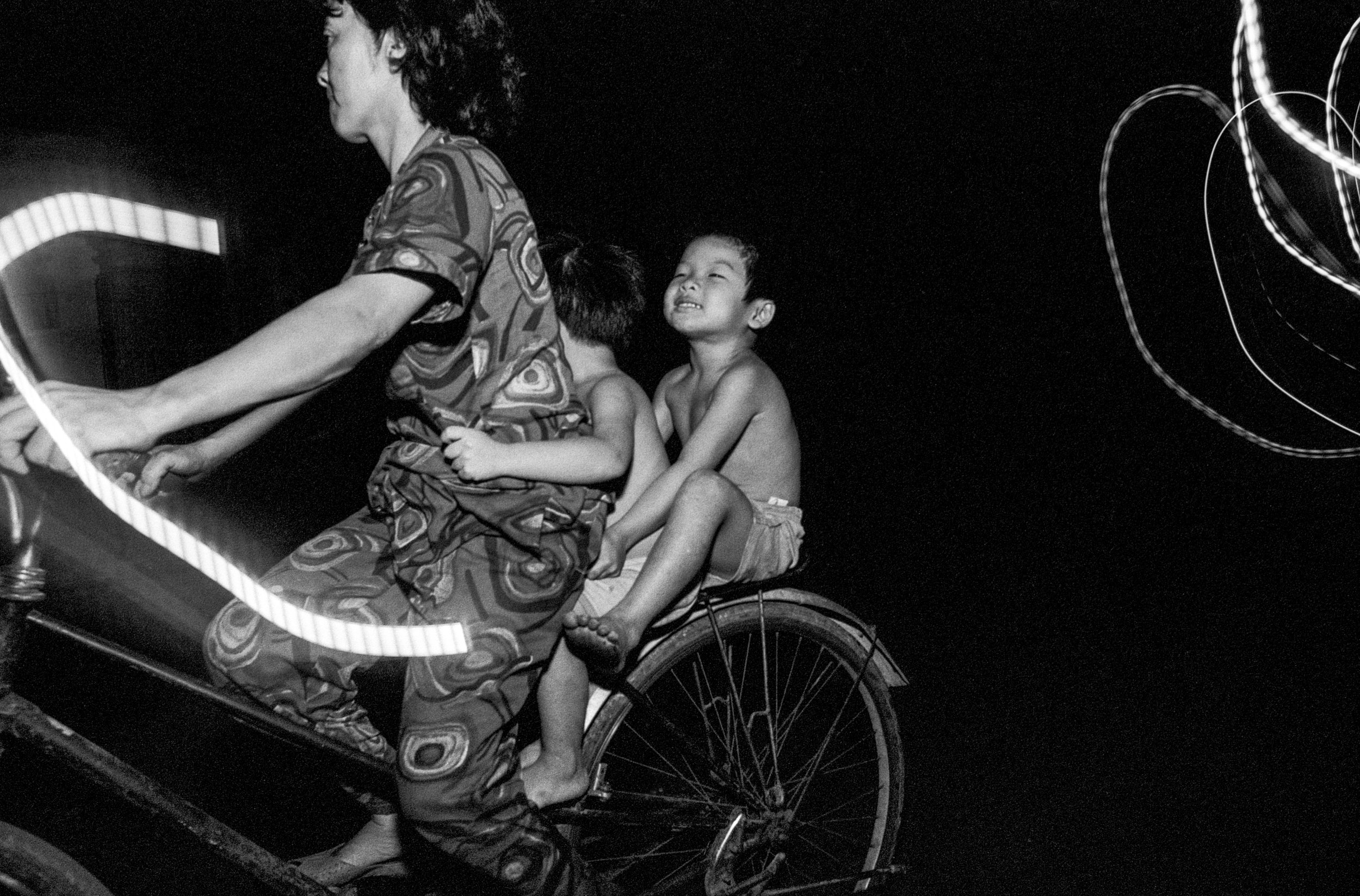  A mother and her two children biking at night in Saigon. 