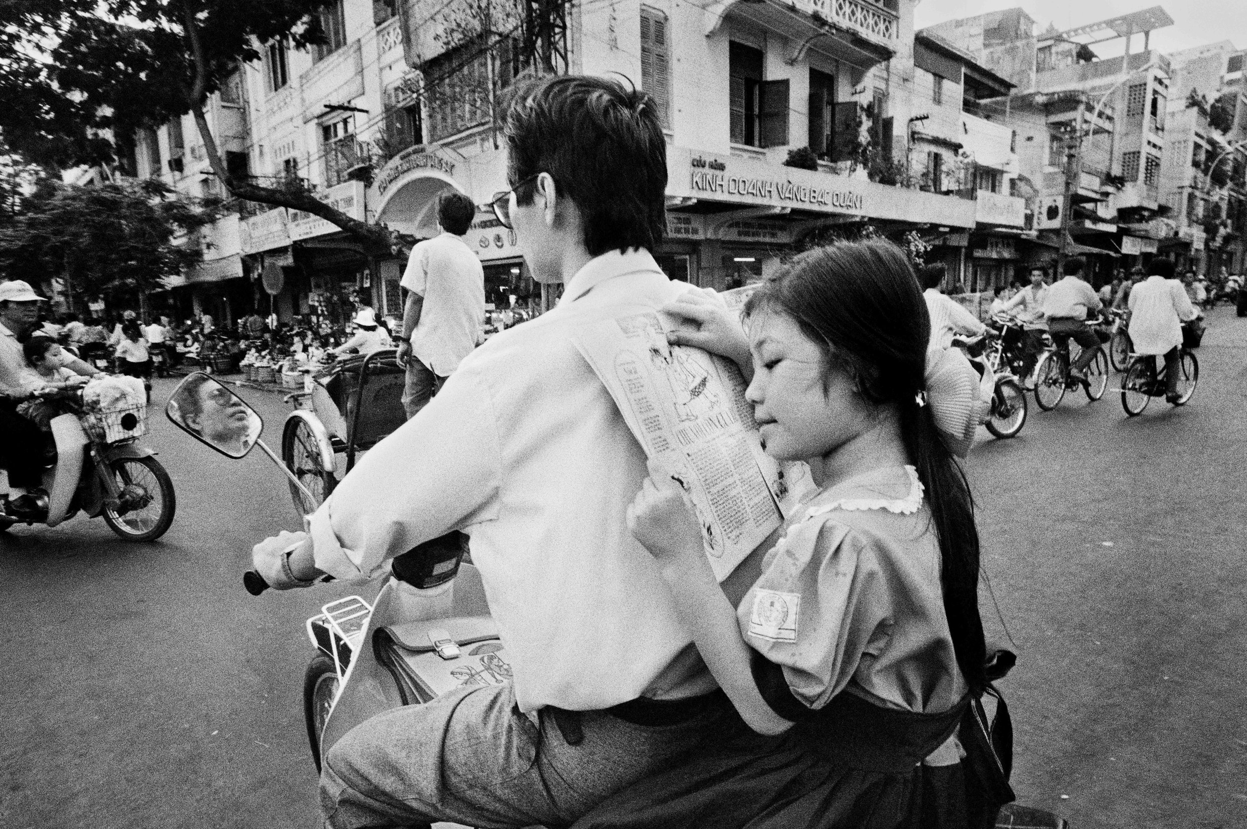  A father’s back makes a comfortable reading stand for this girl on her way to school in Cholon, the Chinese district of Saigon. 