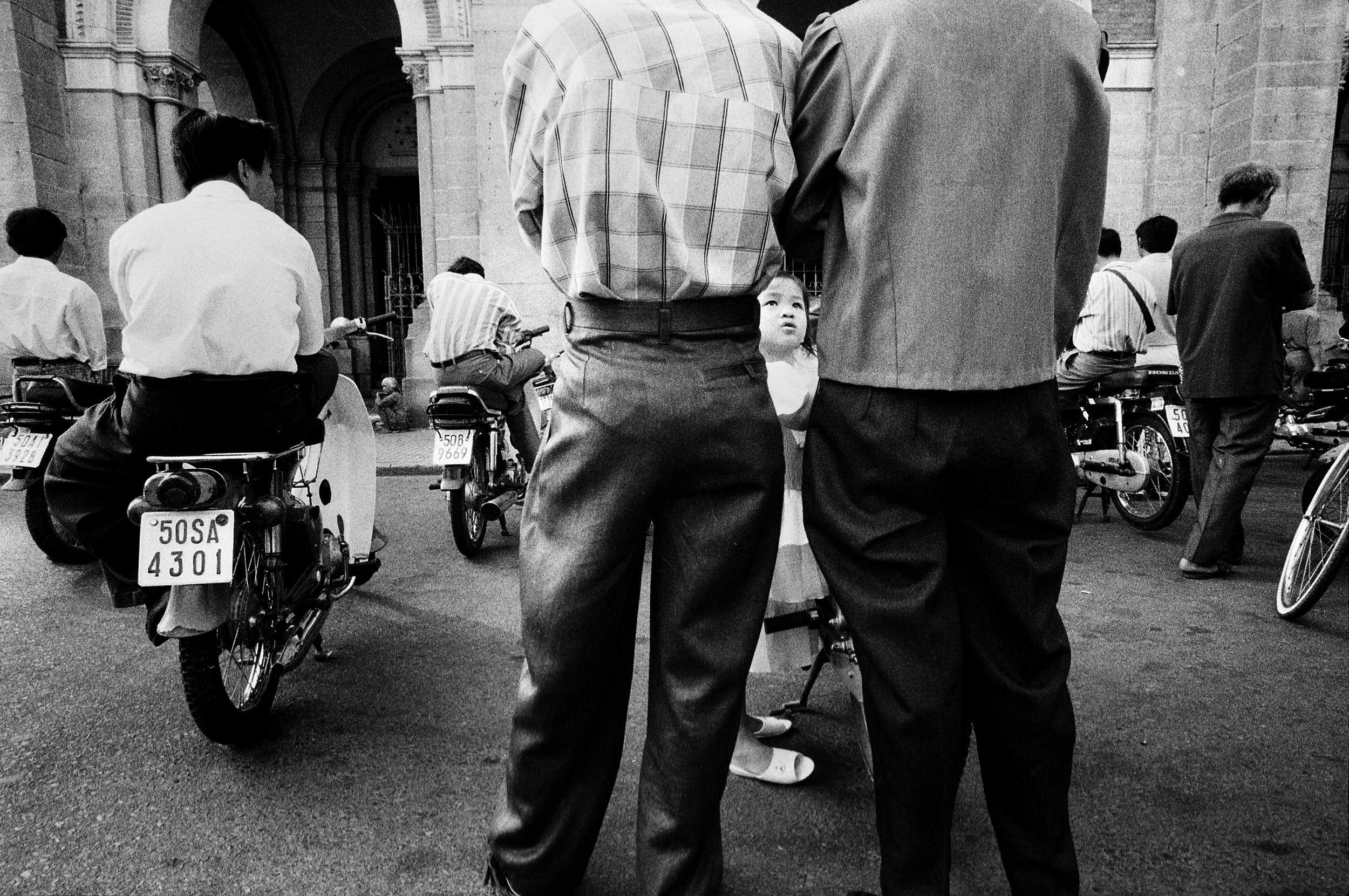  Outside the Duc Ba, or Notre Dame Cathedral, parishioners sit on their motorbikes and listen to mass over the loud speakers. 