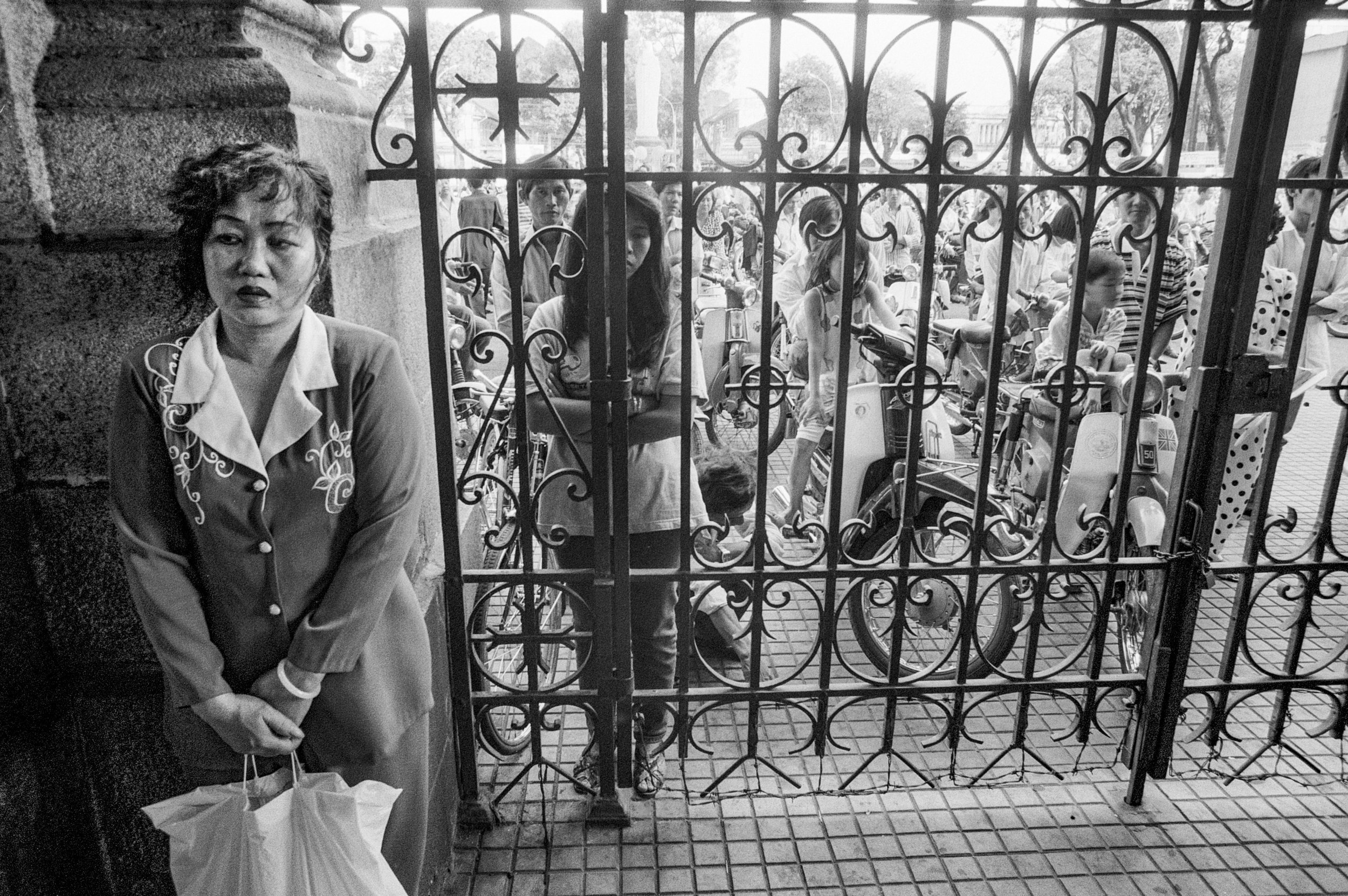  A woman waits to enter the main cathedral in Saigon for midday mass. 