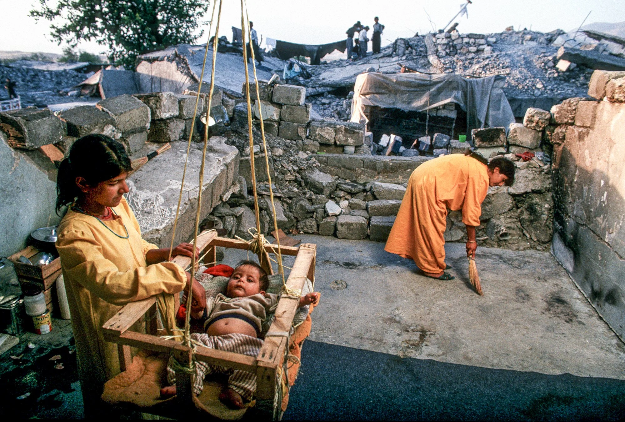 Sabry Ahmed cradles her son in the ruins of Qala Diza, Iraq, 1991. The Iraqi army destroyed this city of over 100,000 residents in the 1980's but after the Gulf War in 1991, its Kurdish residents were able to return and start to rebuild their lives