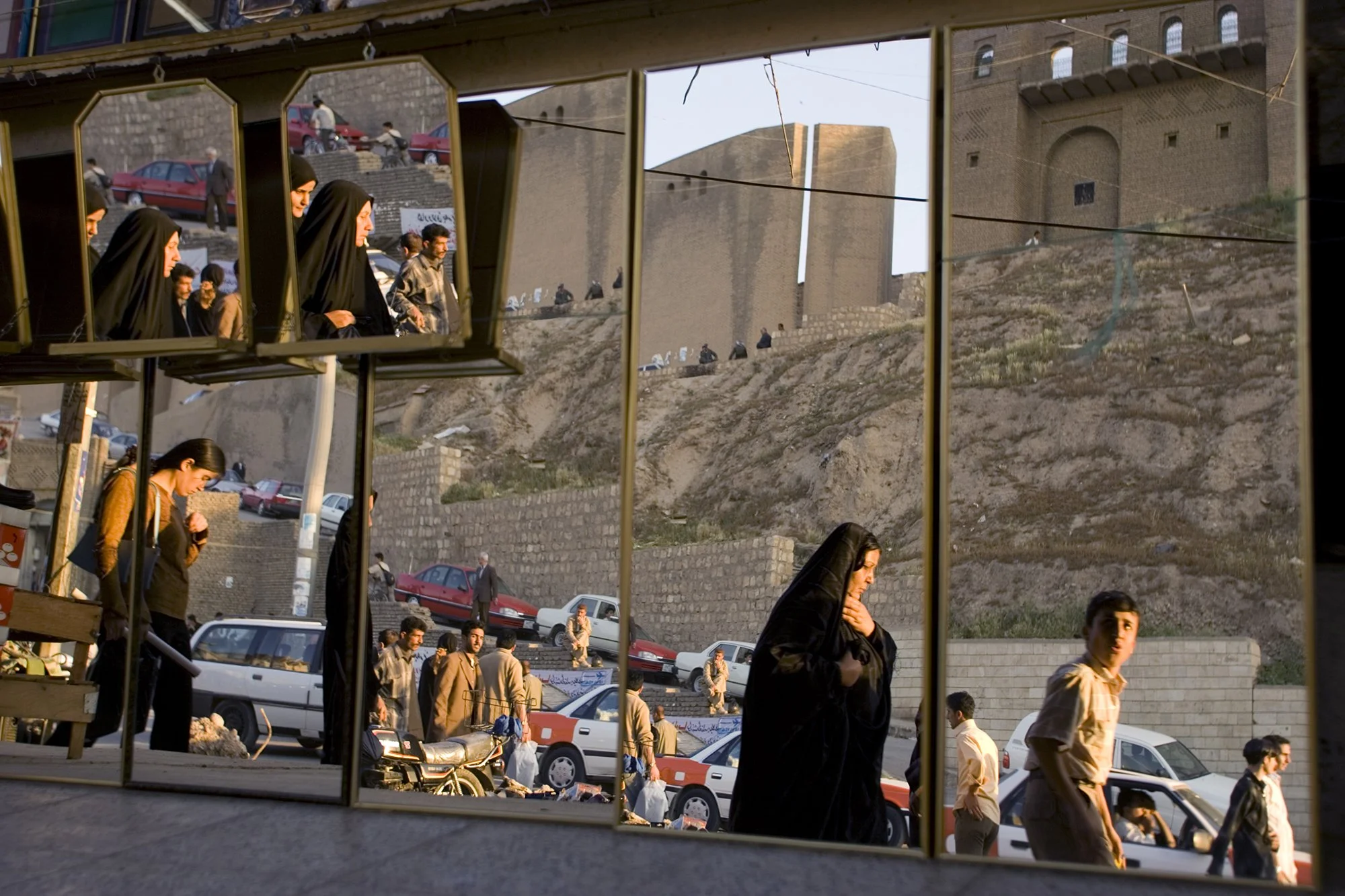 People on the street are reflected in mirrors in the Citadel Frame Shop, opposite Arbil's historic citadel, in Arbil, Iraq on April 17, 2005.