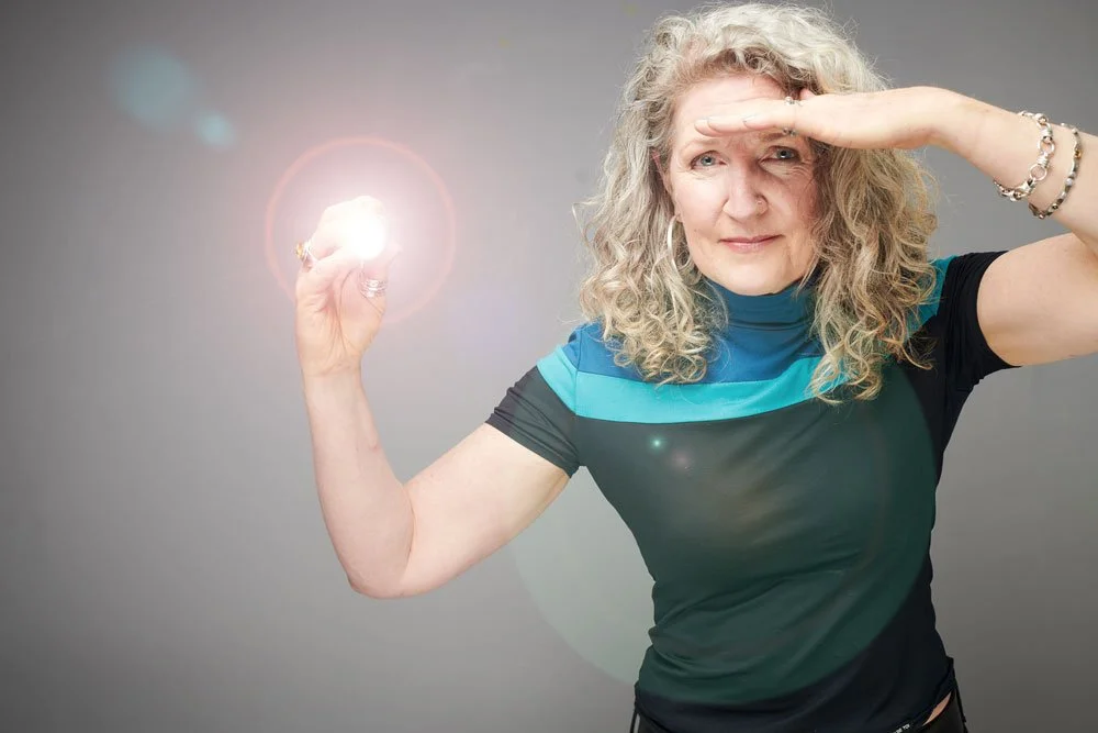 Woman shielding her eyes with one hand and holding a glowing light in the other