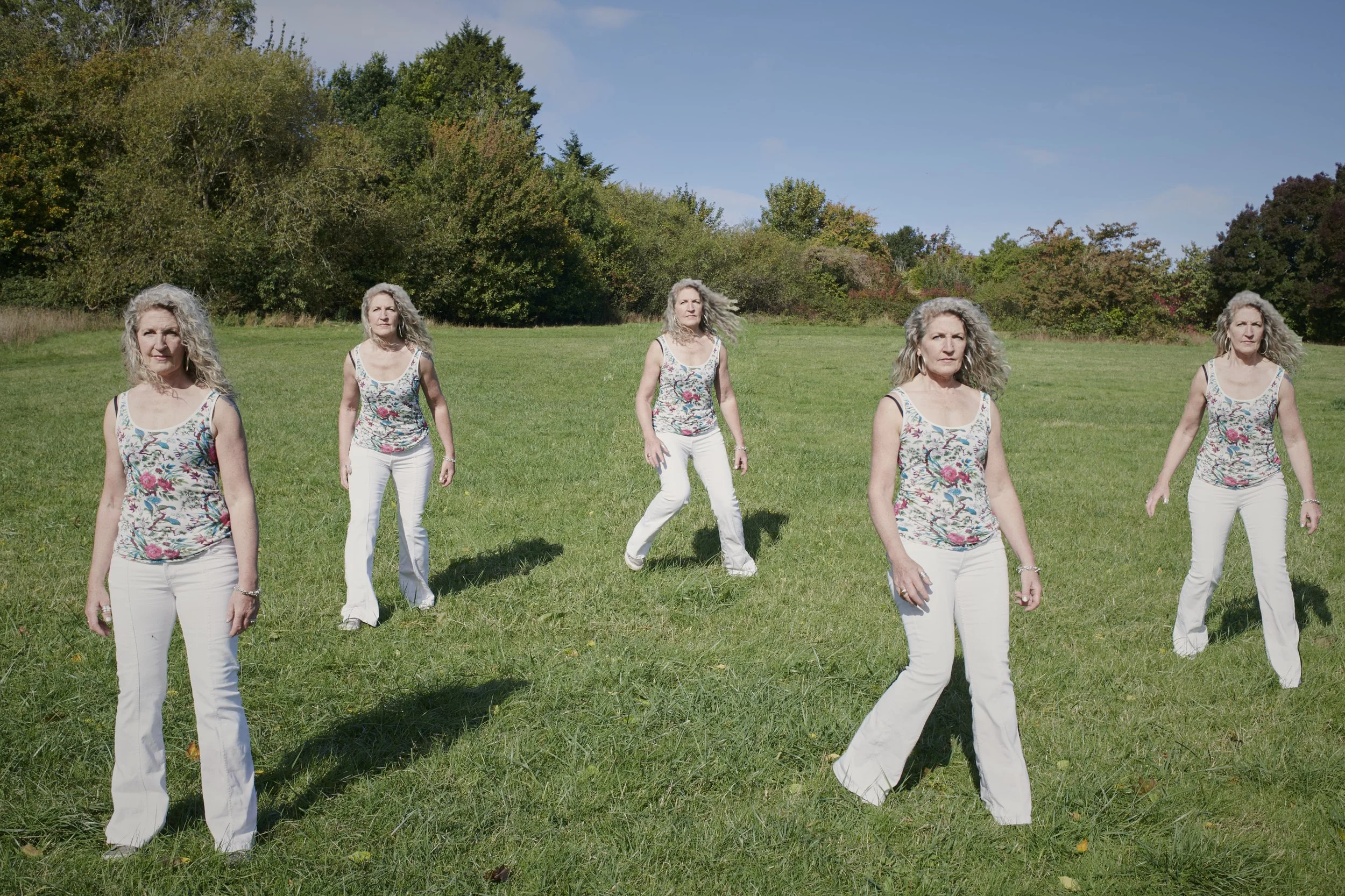 Composite image of the same woman appearing five times as she walks across a grassy field