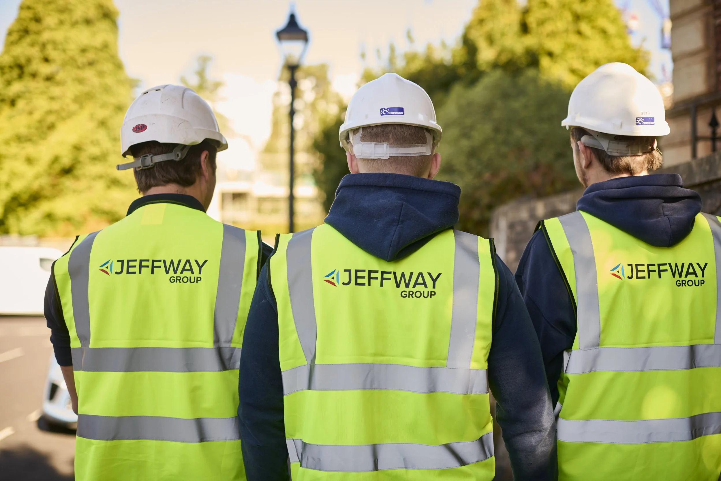 Three Jeff Way Group engineers in branded hi-vis jackets, seen from behind